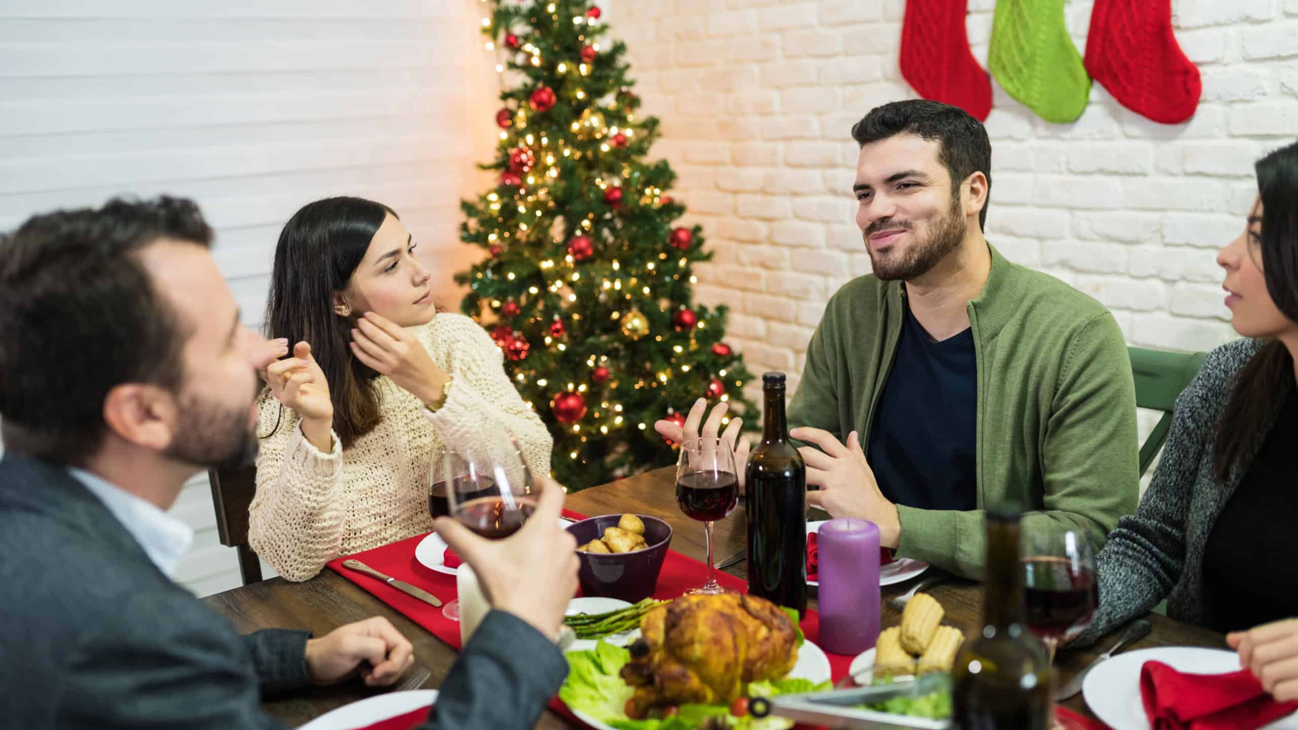 Man talking to friends while enjoying dinner at home during Christmas celebrations