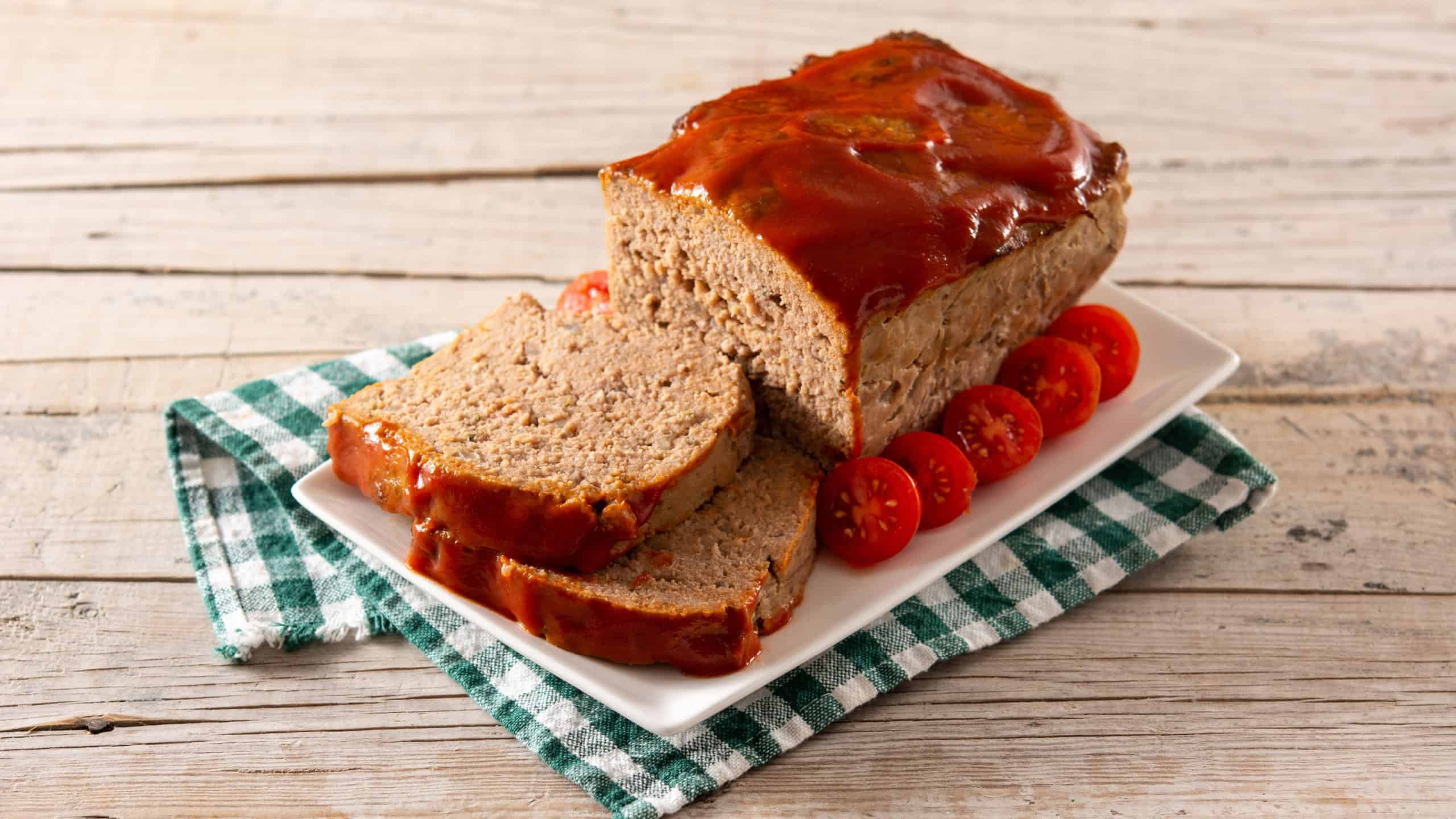 Traditional American meatloaf with ketchup on rustic wooden table