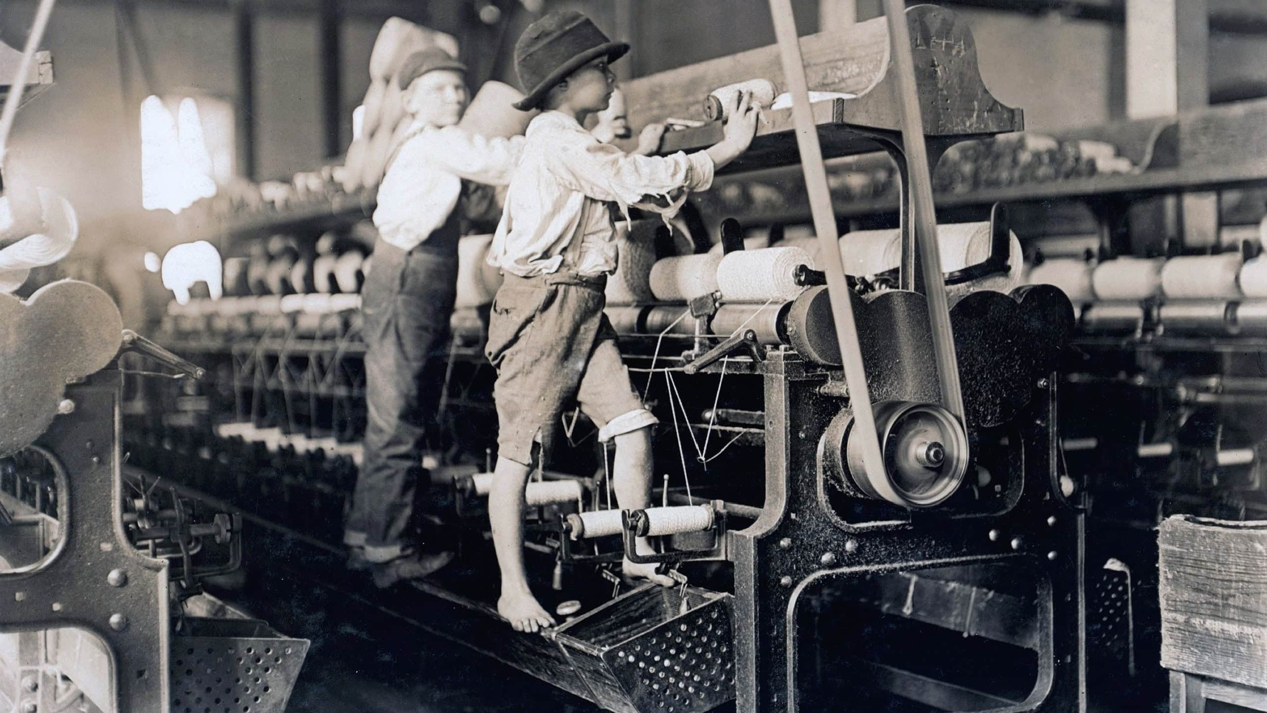 Child laborer portrayed by Lewis Hine in 1909. Barefooted boy in a George cotton mill was so small he had to climb up on the spinning frame to mend the broken threads and put back the empty bobbins.