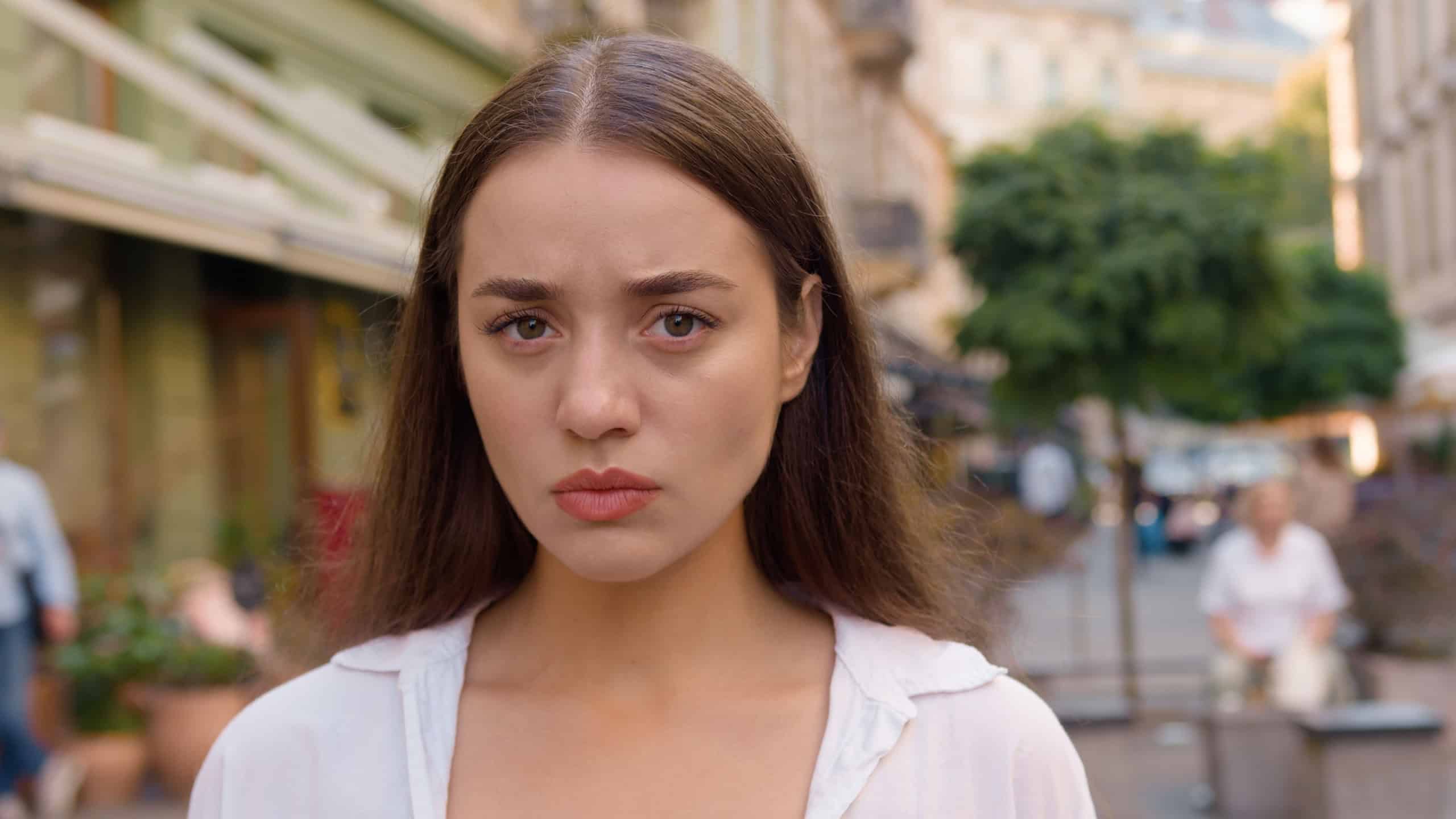 Close up Caucasian unhappy girl street city annoyed woman frowning emotions displeased disappointed dissatisfied angry female envy irritation bad reaction serious expression confident negative pensive