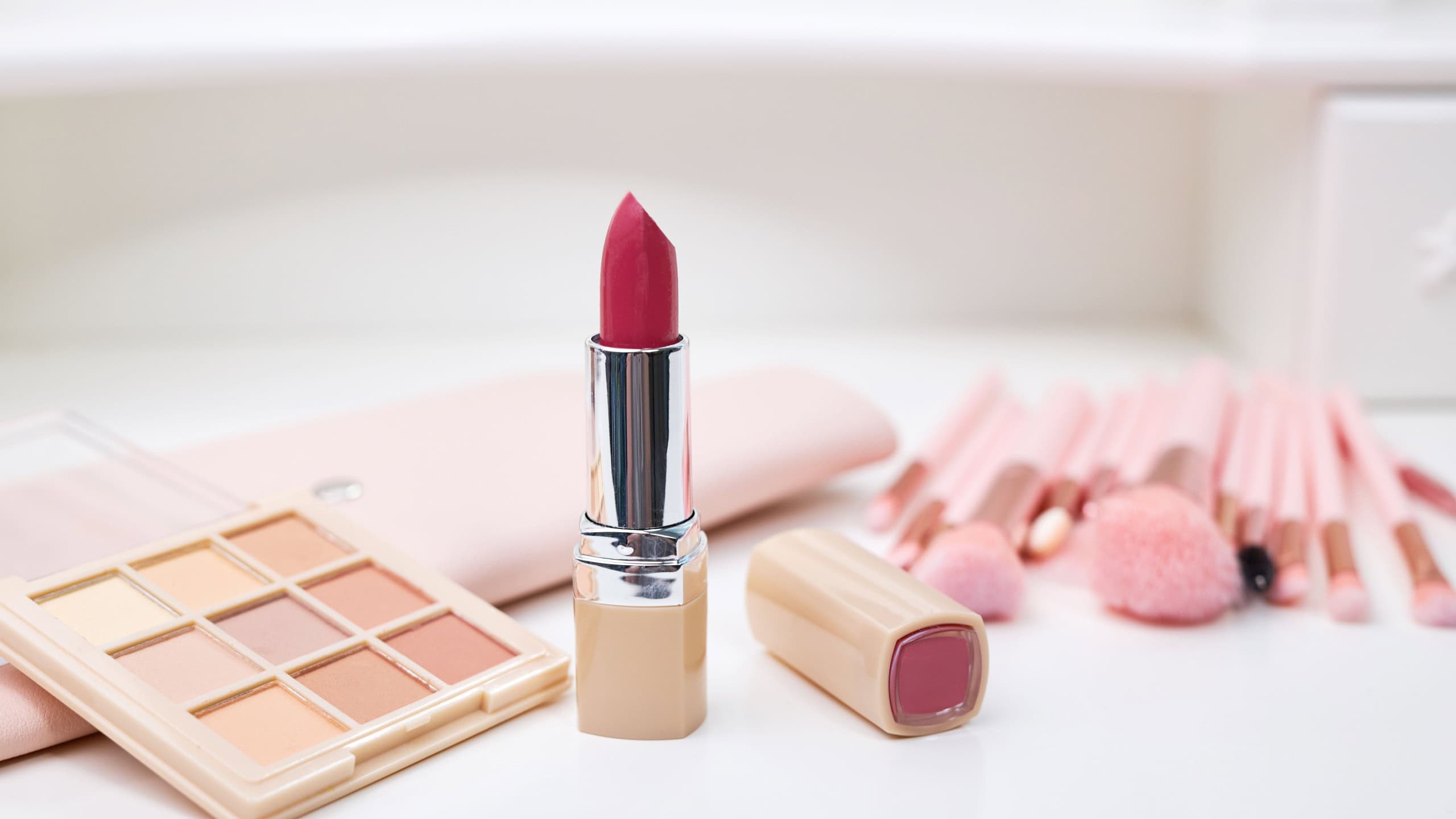 Set of decorative cosmetics on a white table, brushes, eye shadow and lipstick. Decorative cosmetics on dressing table in makeup room