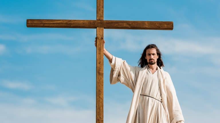 handsome man standing and holding wooden cross