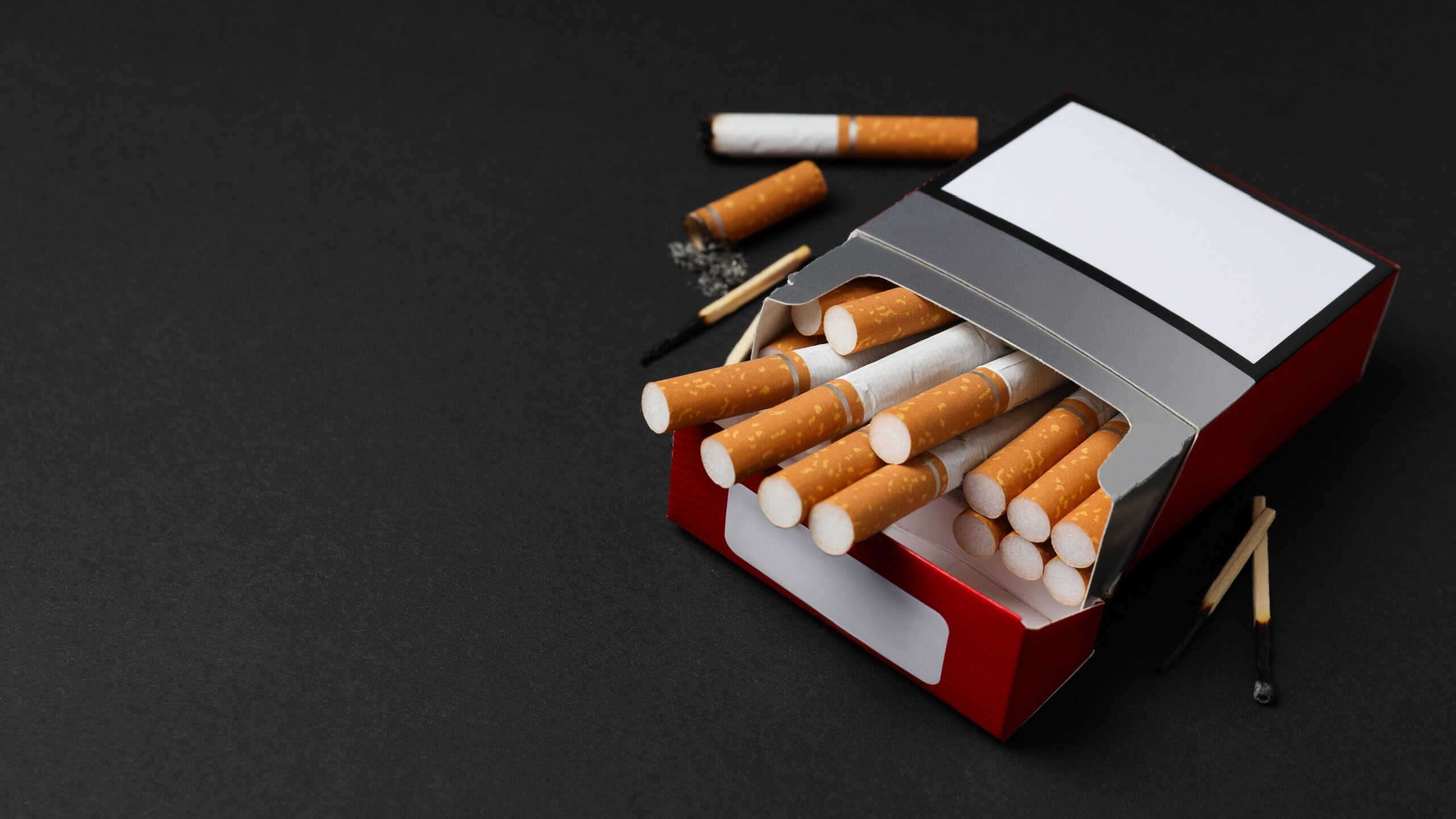 A pack of cigarettes with matches on a dark background