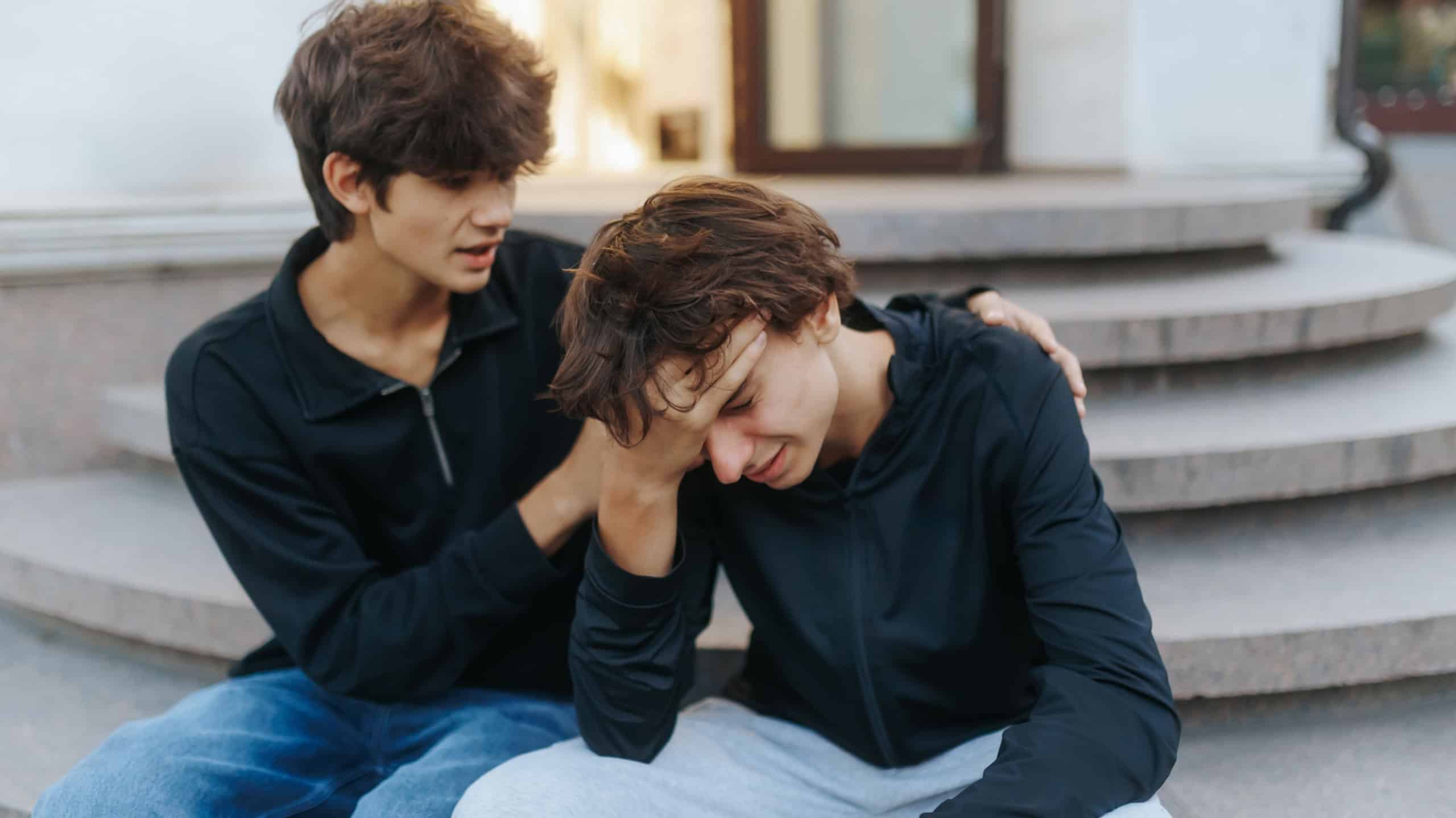 A caring teen comforts his sad and hopeless friend outdoors, symbolizing trust, empathy, and strong emotional bonding in a friendship during tough times.