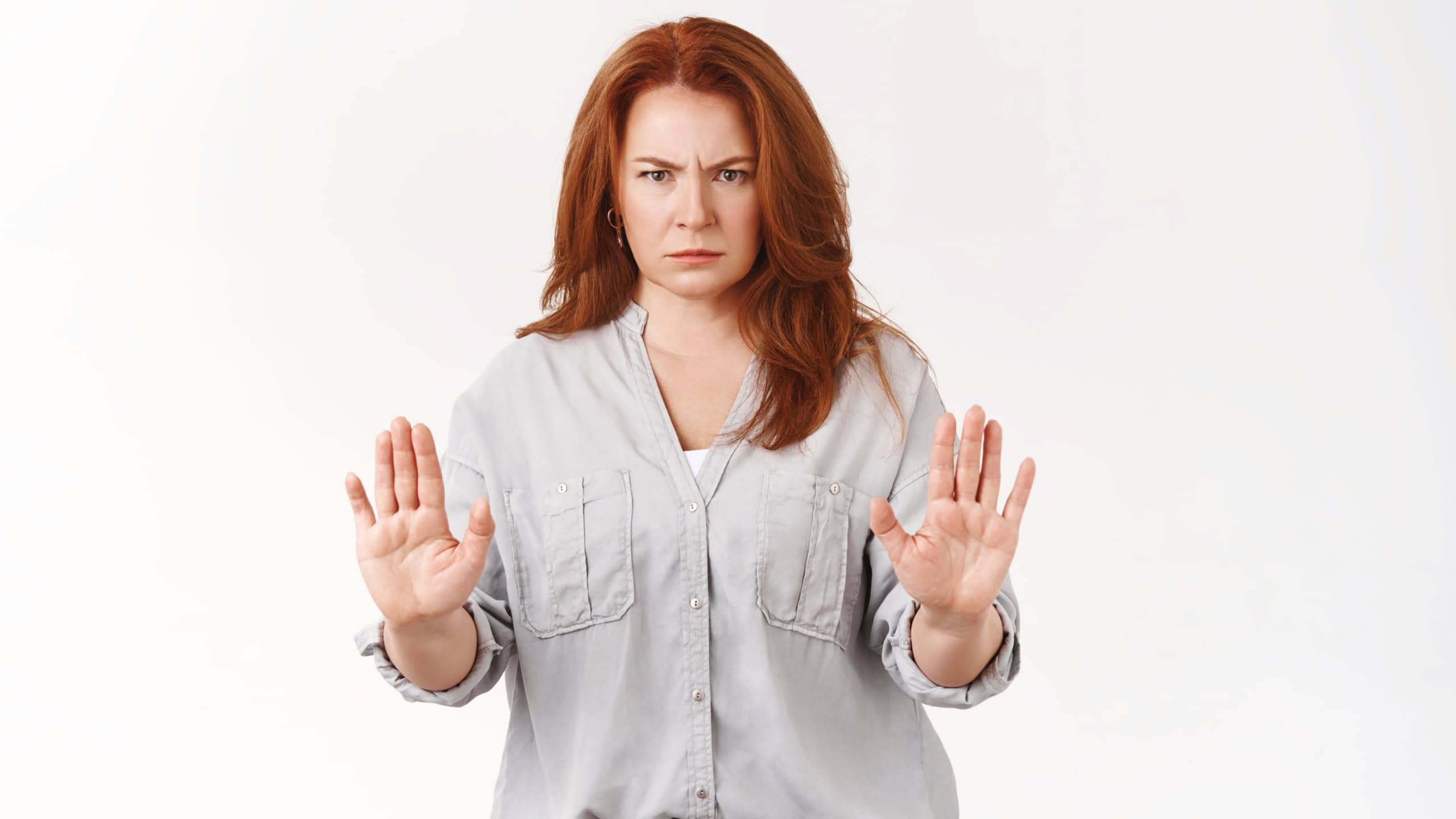 Stop right there. Serious-looking mad middle-aged redhead mother caught son smoking forbid raise hands prohibition warning gesture frowning angry stare camera express taboo strong refusal