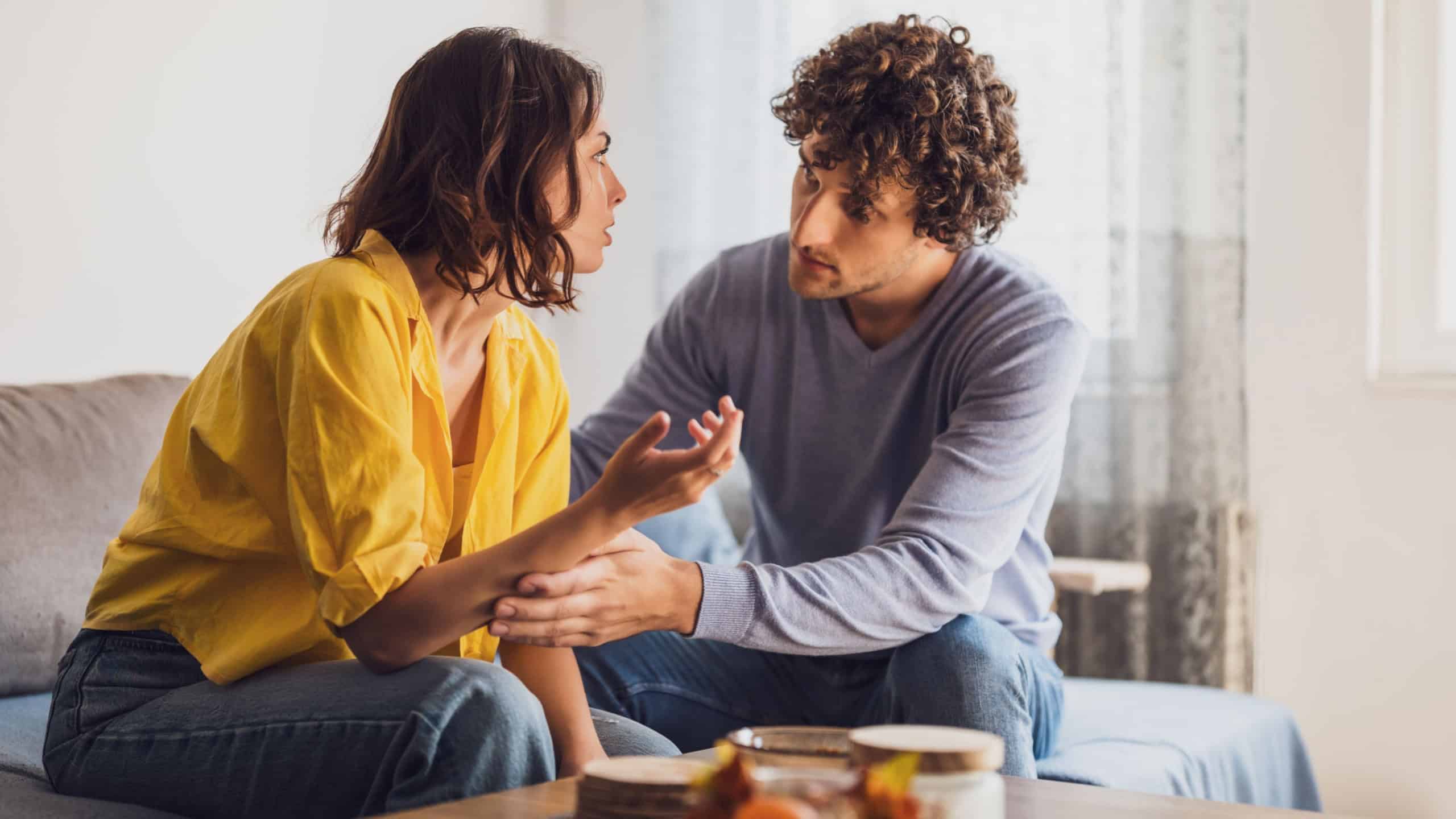 Man and woman are sitting at sofa and arguing. Relationship problems.