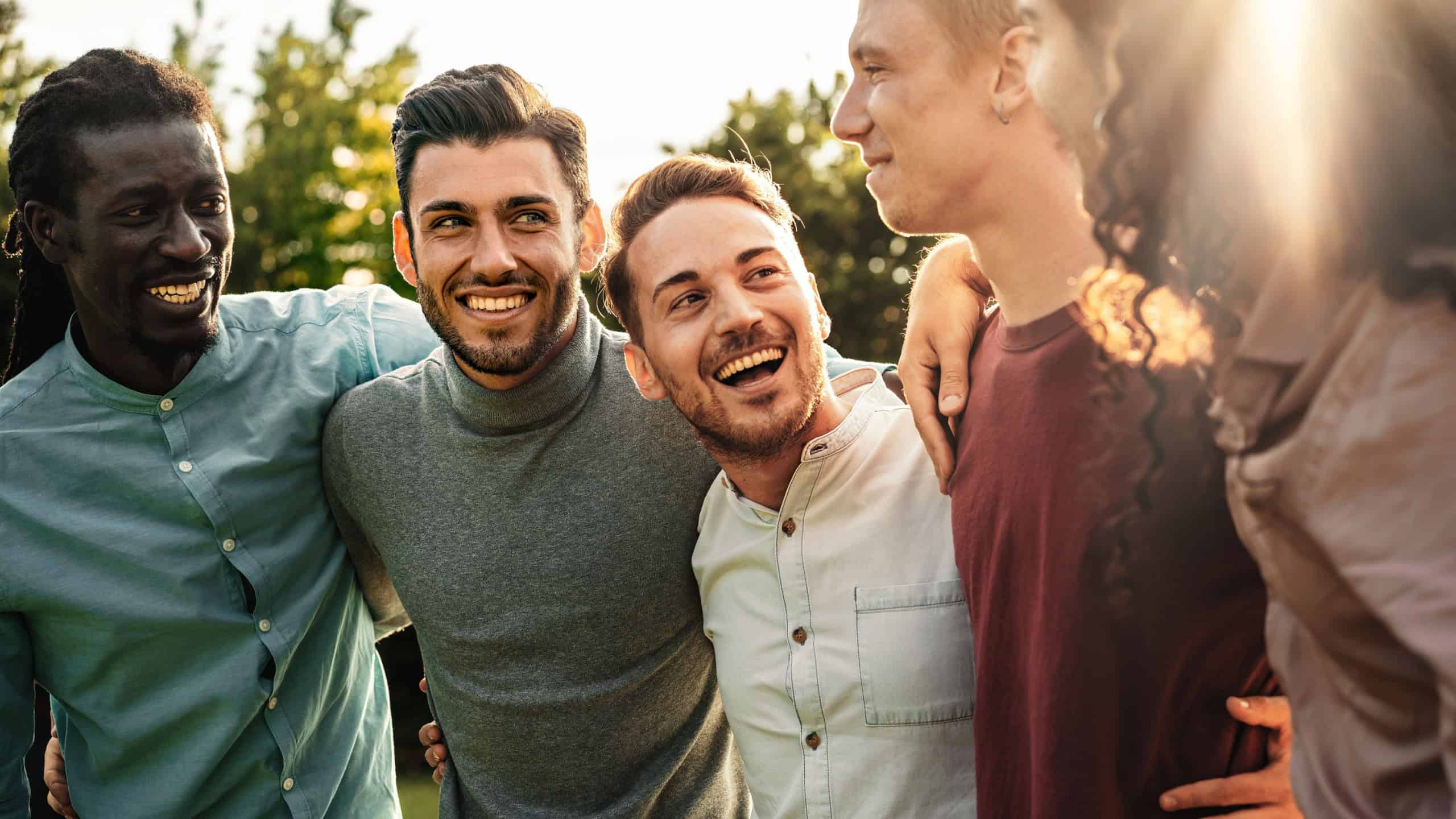A group of joyful male friends bonding and laughing together in an outdoor setting, radiating friendship and happiness.
