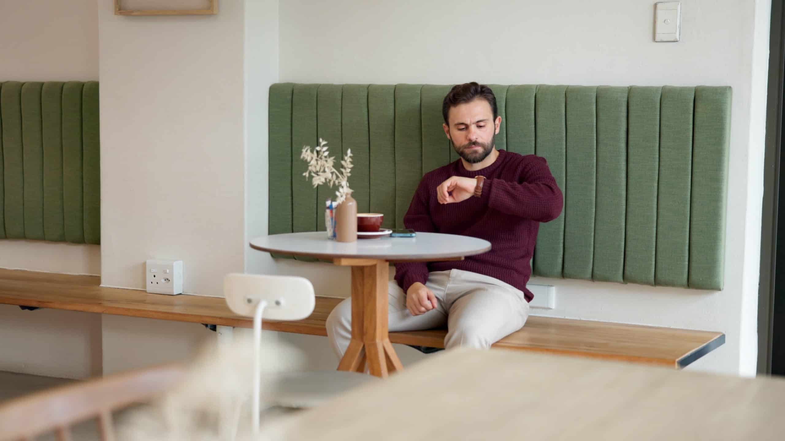 Thinking, waiting and time with man in cafe for customer service, lunch order and date. Hospitality, reflection and late appointment with person in coffee shop for wristwatch, cafeteria or restaurant