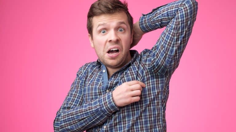 Caucasian, young man is worried and shocked because of sweating stain. problem with hyperhidrosis. Studio shot on pink background