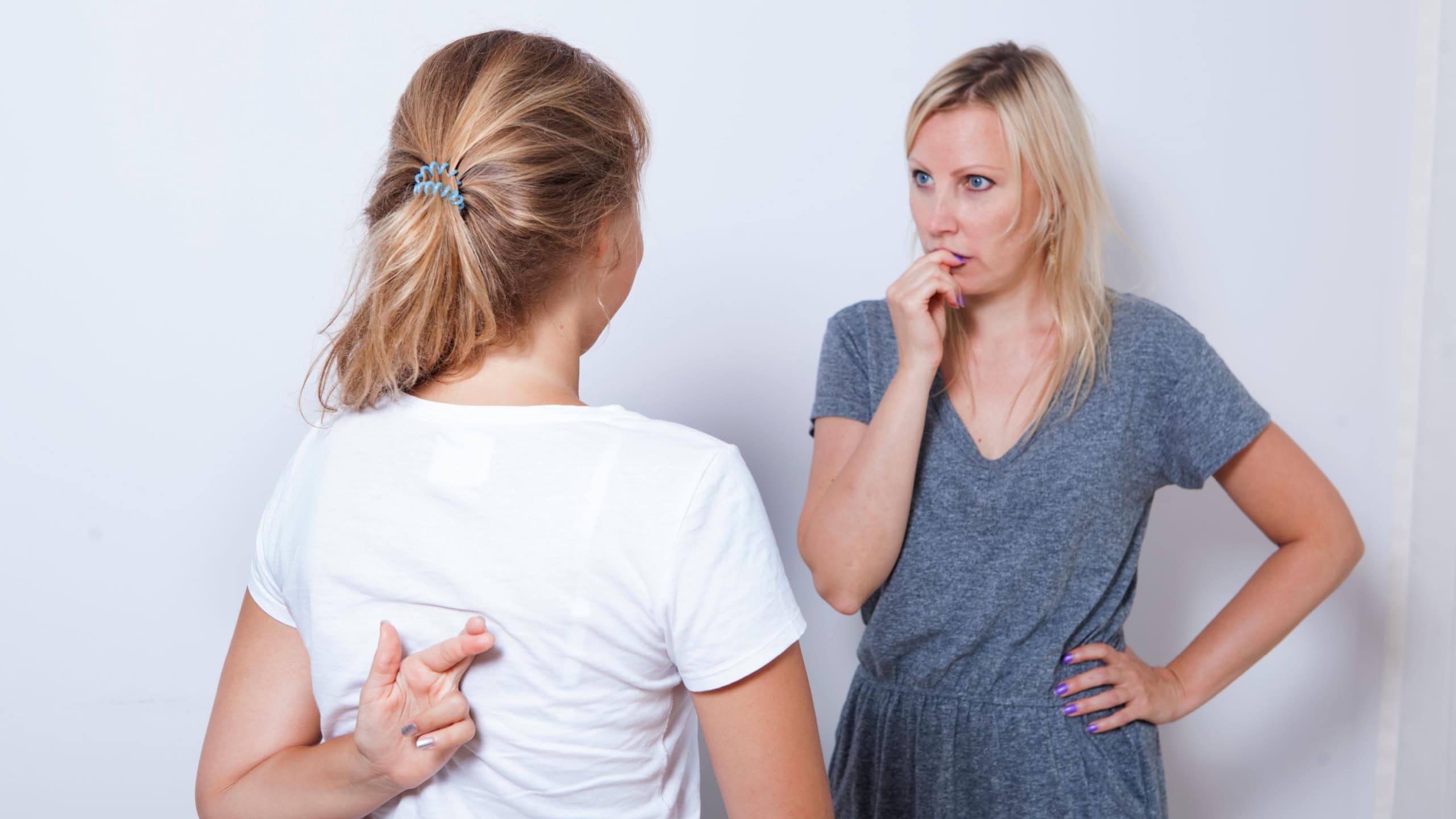 Mother asking her teenage daughter. Girl wants to lie to her parent and crossed her fingers.