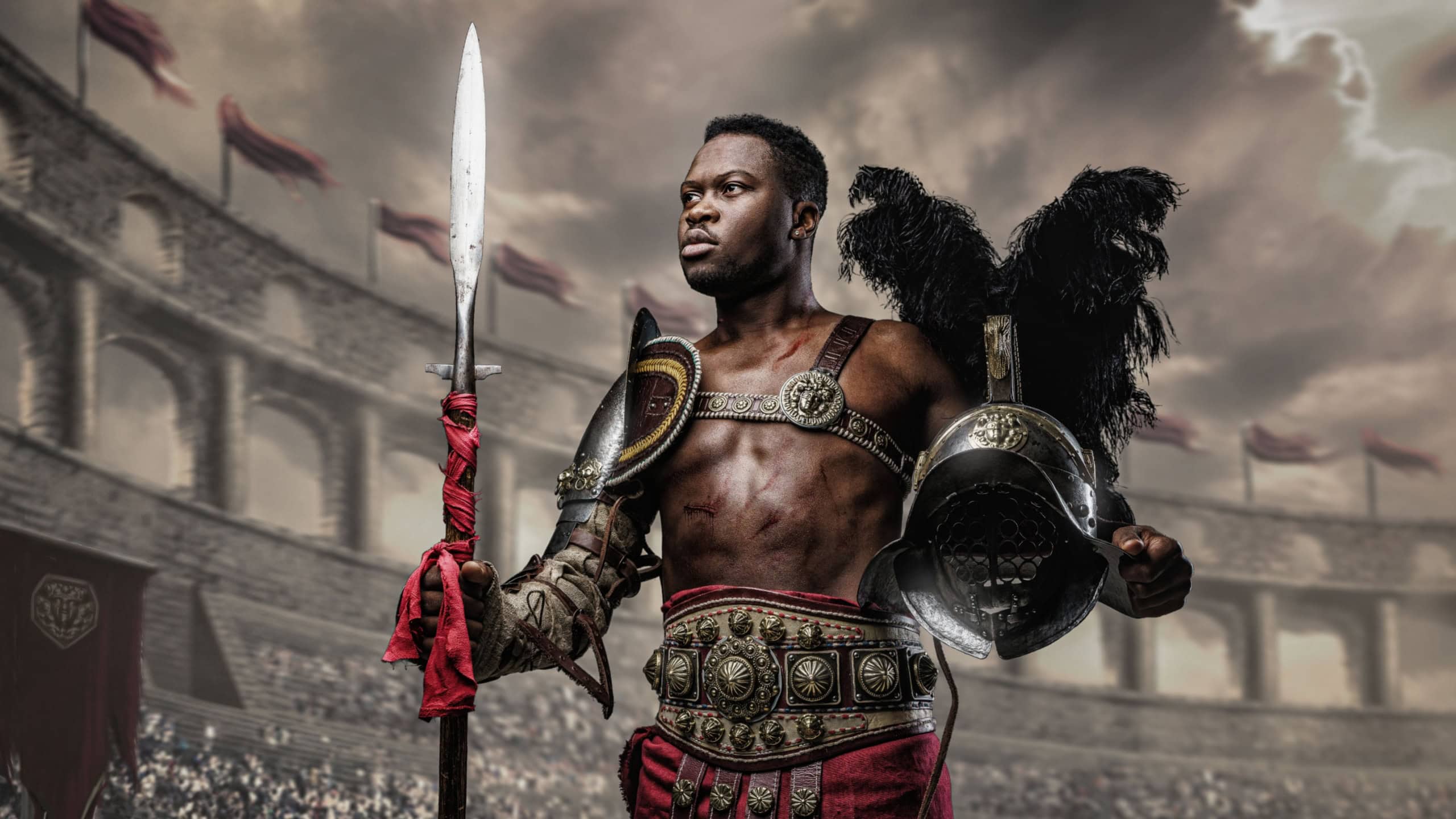 Portrait of victorious gladiator of african ethnic holding plumed helmet and spear in coliseum.