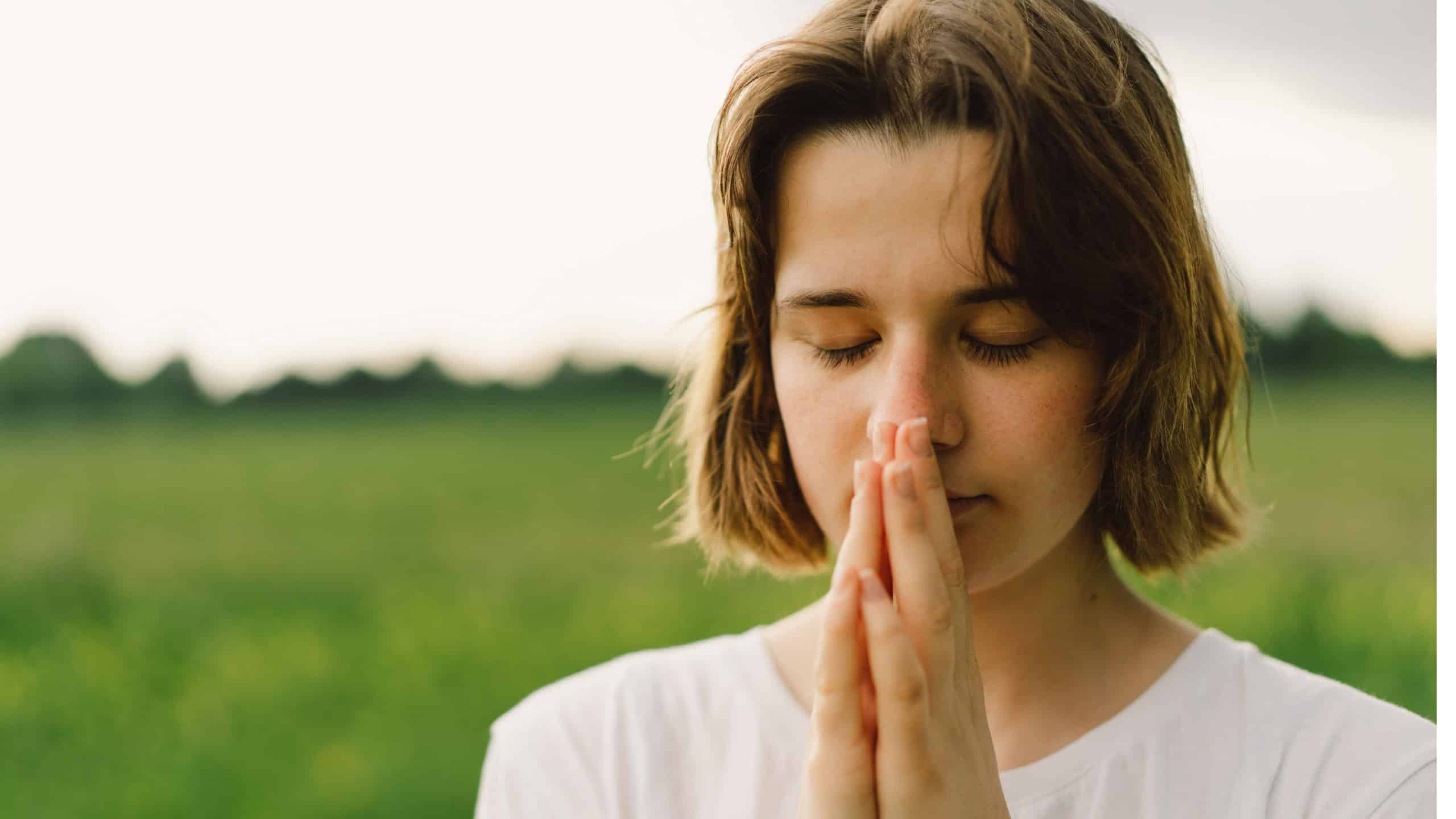 Teenager Girl closed her eyes, praying. Hands folded in prayer concept for faith, spirituality and religion. Peace, hope, dreams concept