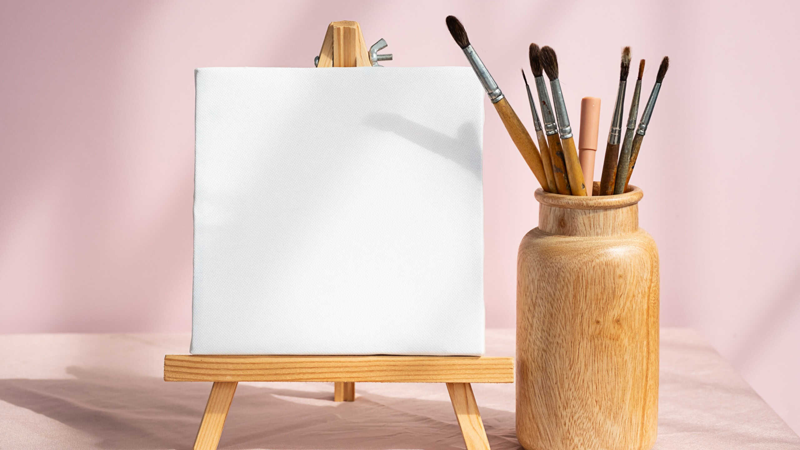 Blank white canvas and vase with paintbrushes for art. Artistic layout.