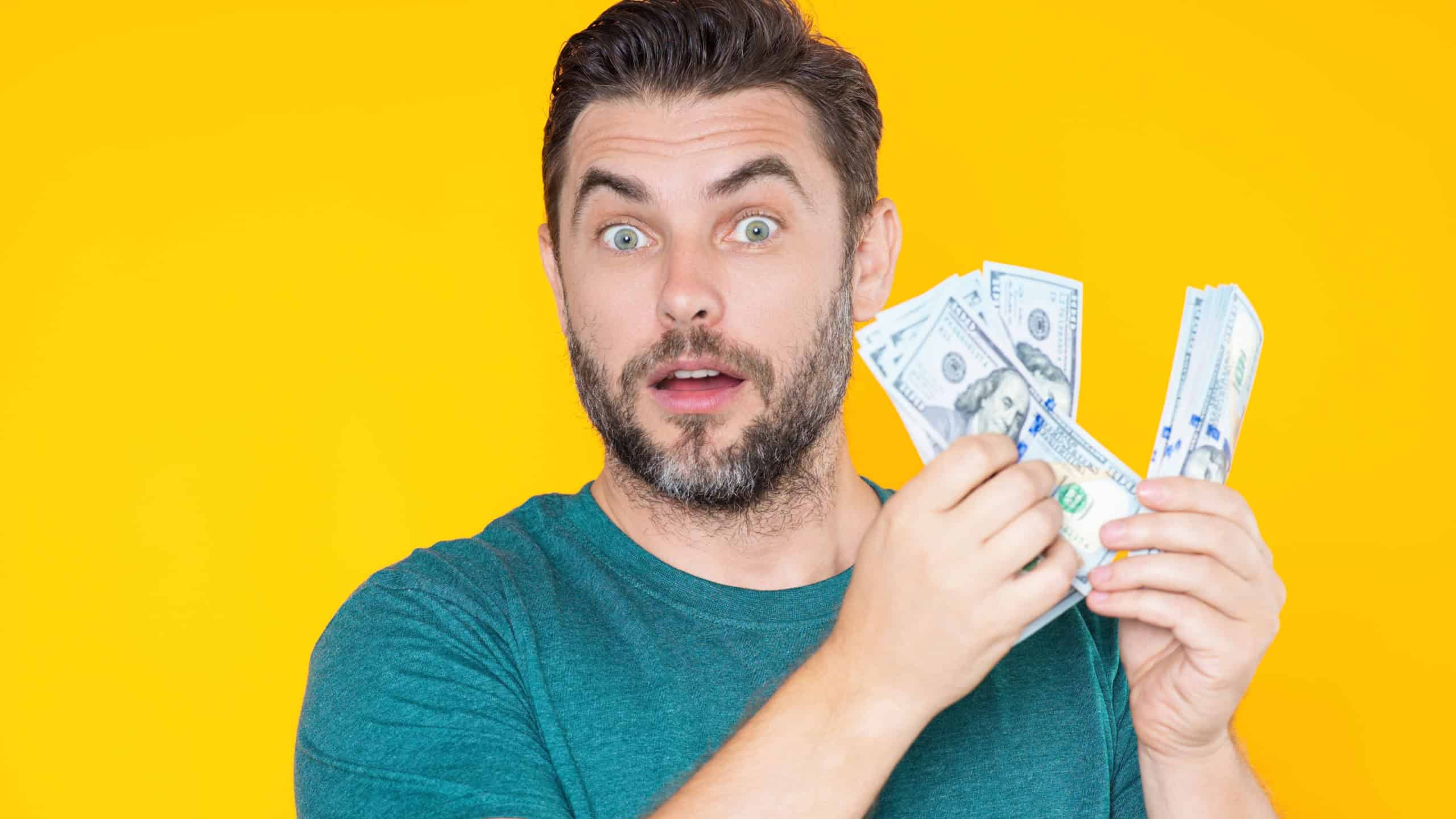 Man hold money on yellow studio isolated background. Portrait of rich man with money dollar bills. Successful guy with dollar banknotes. Rich millionaire holding money.