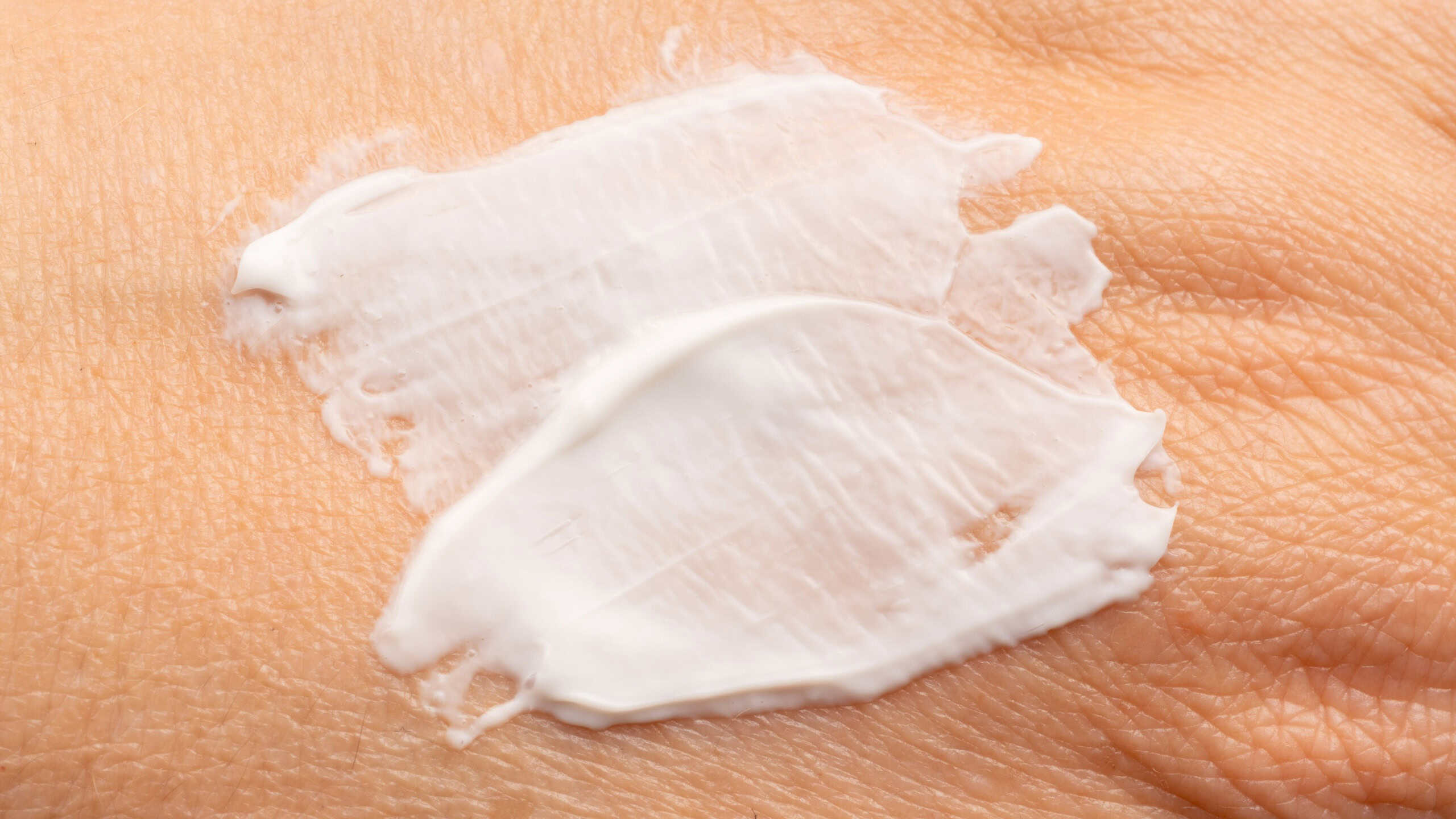 Applying skin cream close up. Body care lotion smear on dry skin, skincare moisturizer cosmetics or sunscreen creme applying, wrinkle protection texture background for dermatology design