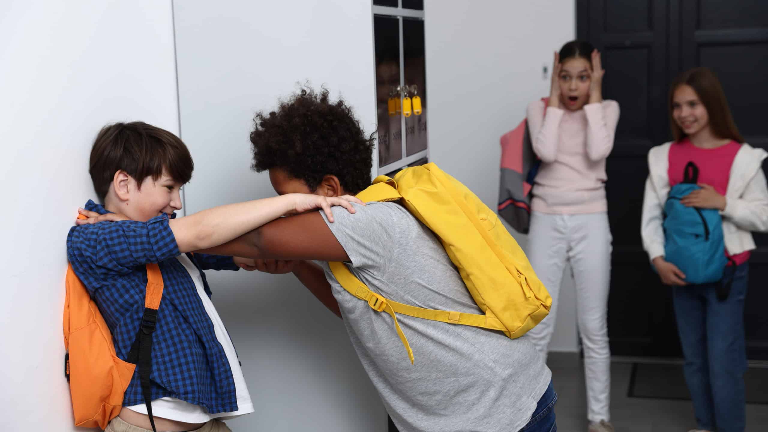 Bullying. Boy fighting with his African American classmate in school