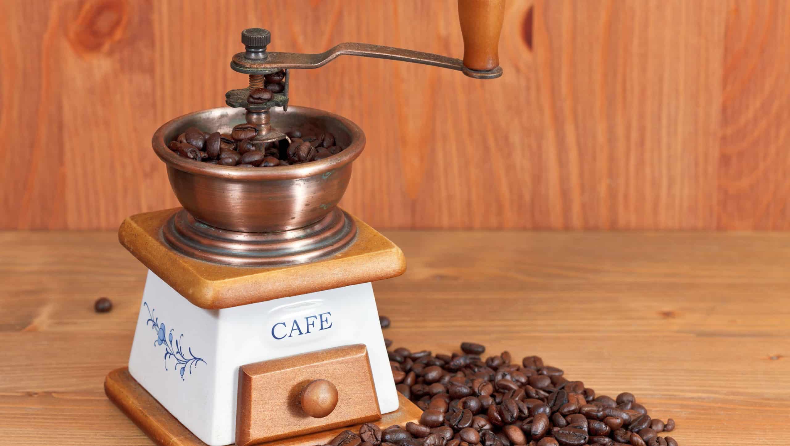 heap of coffee and vintage manual coffee mill on wooden table