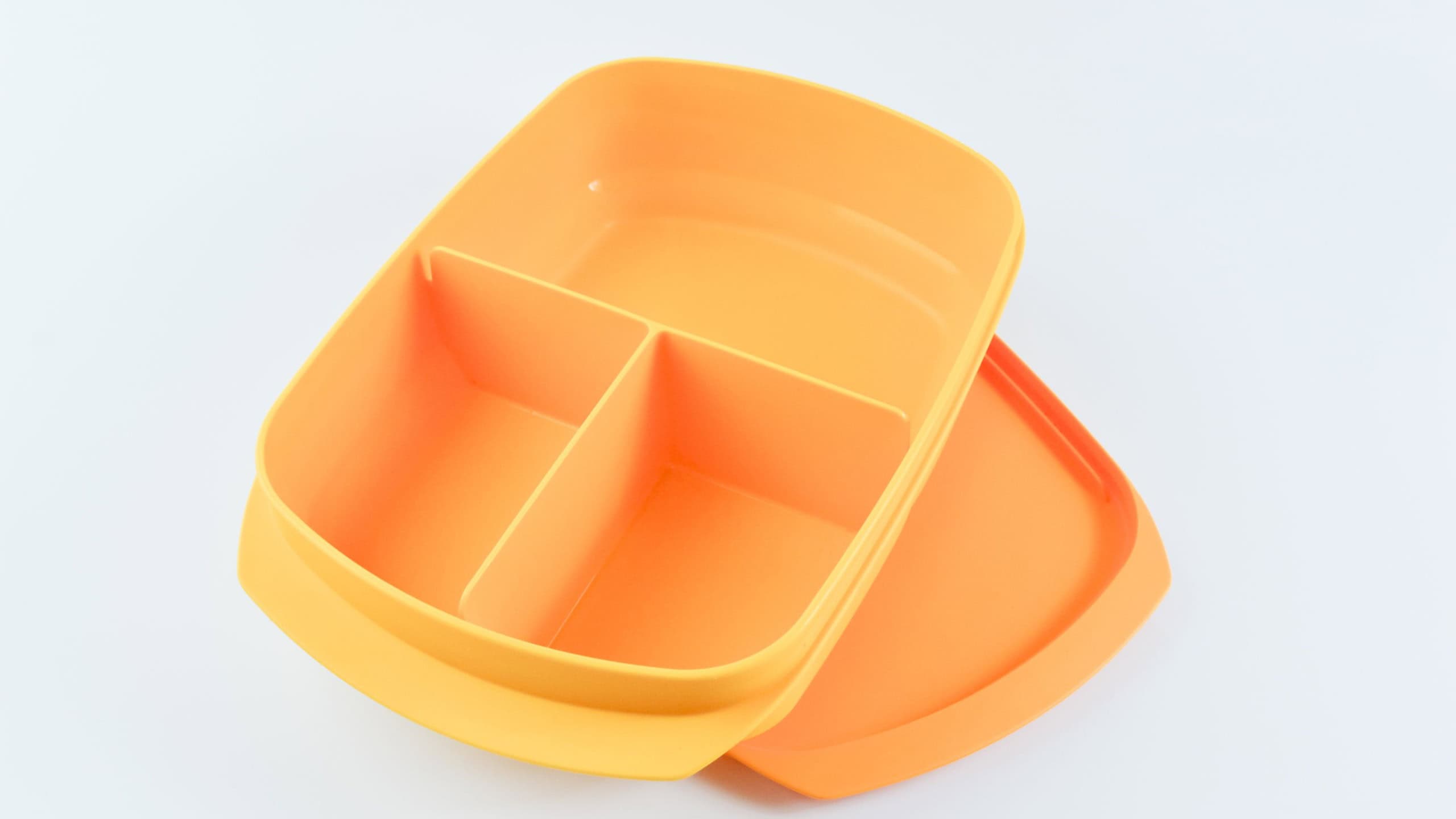 - Yellow plastic food containers isolated on a white background. Tupperware brand