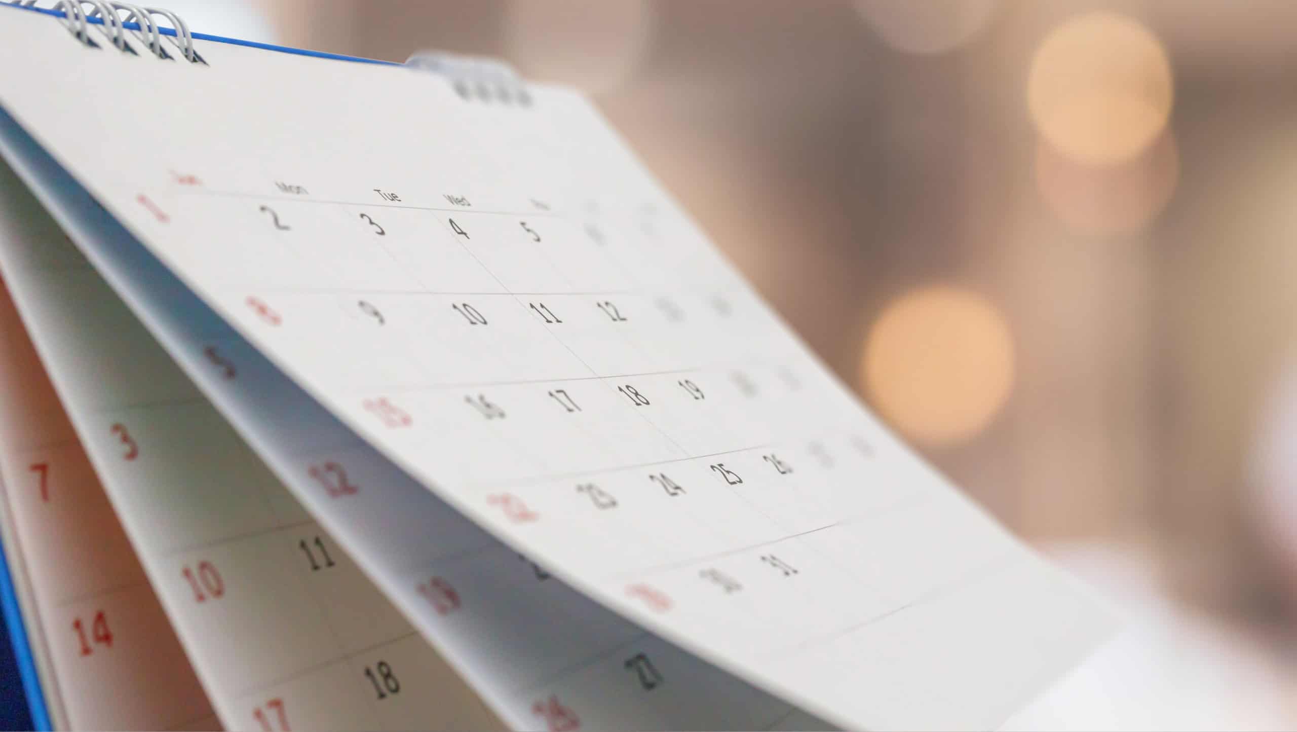 Close up white paper desk calendar with blurred bokeh background appointment and business meeting concept