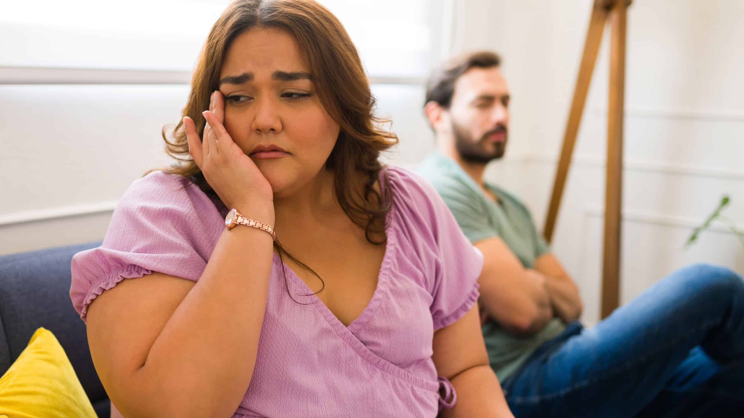 Crying latin woman feeling sad because of relationship problems after arguing with her angry boyfriend
