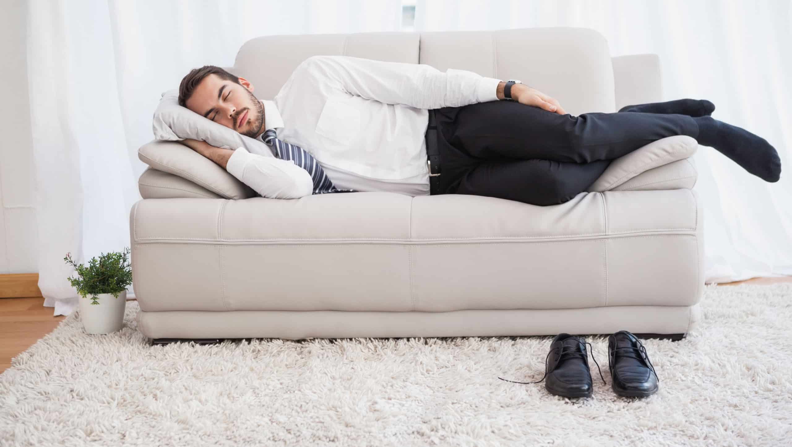 Businessman sleeping on couch after long day at home in the living room