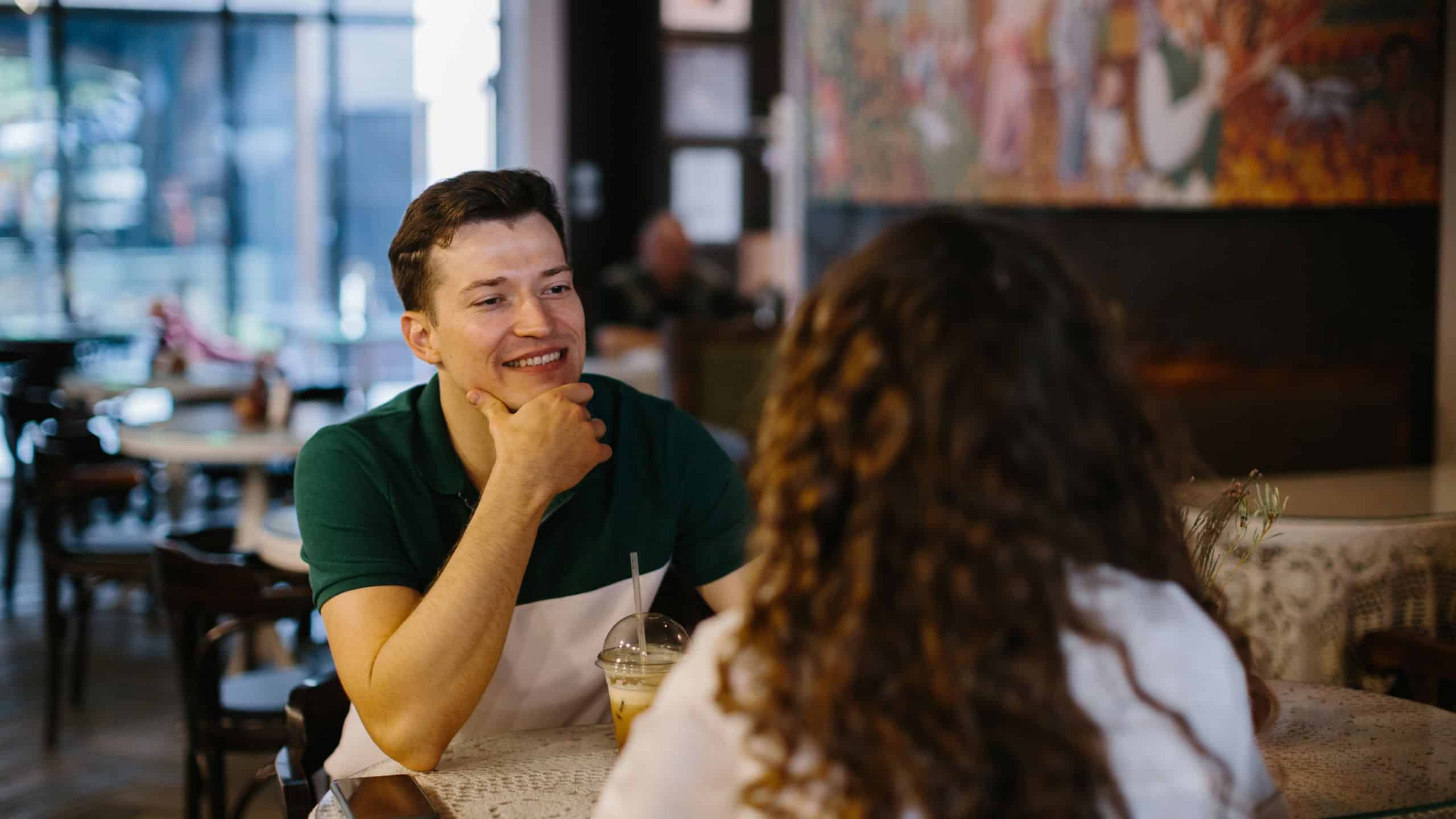 Happy young couple talking over a cup of coffee in a cafe, man and woman in a coffee shop on a date.