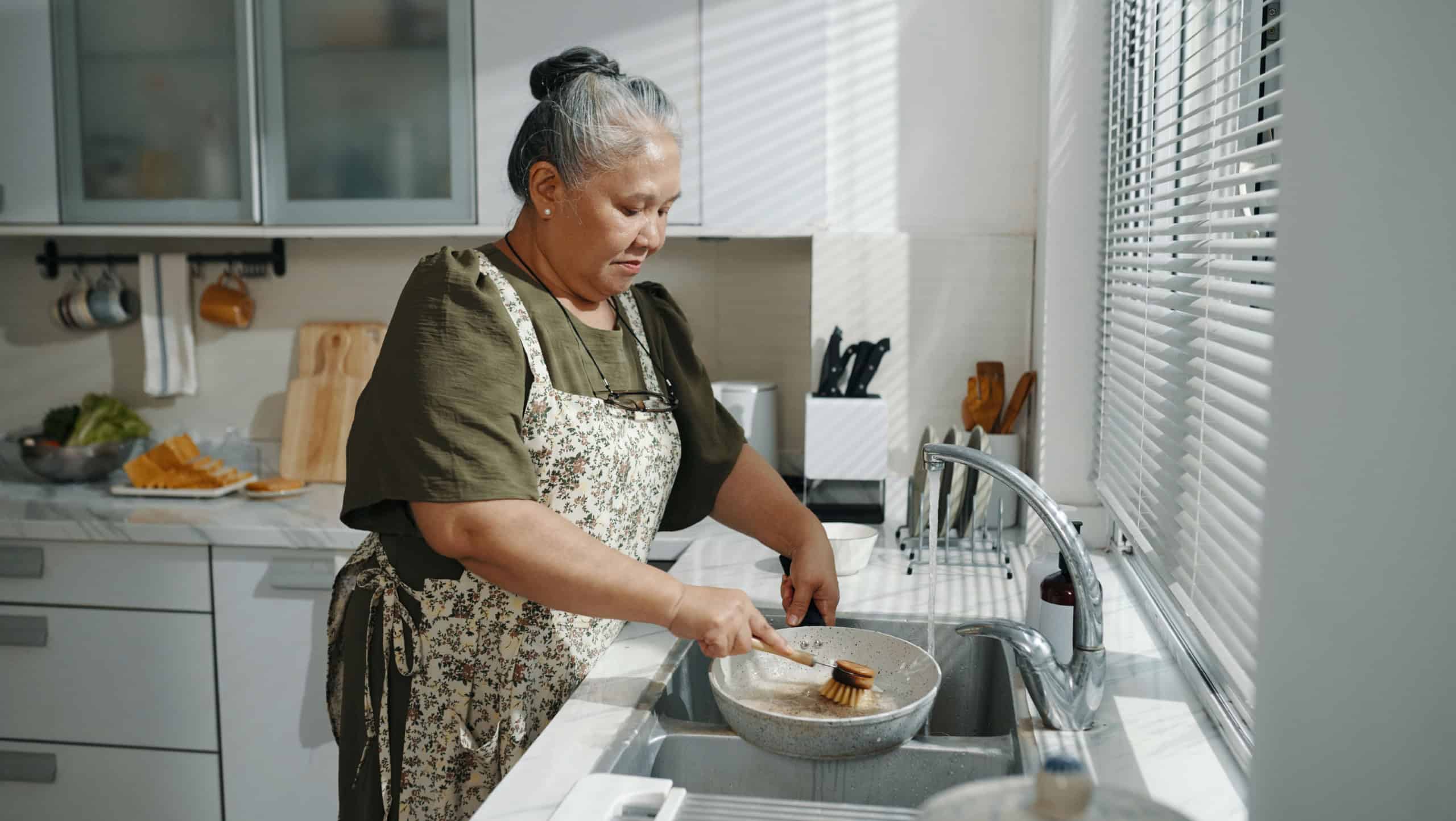 Senior Woman Washing Dishes In The Kitchen