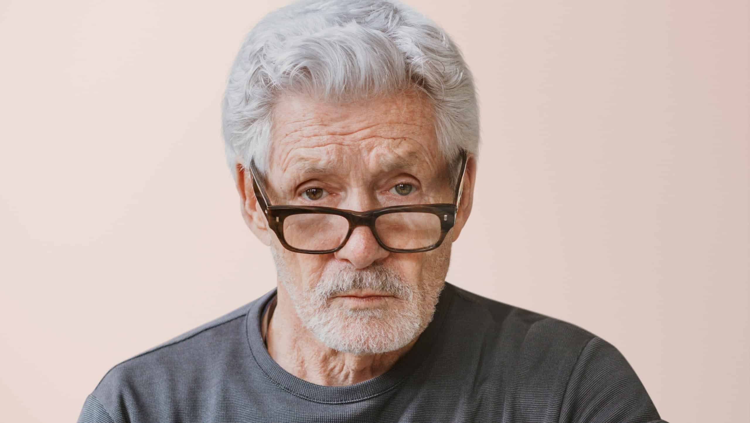 Serious teacher wearing glasses, isolated on pink . Senior caucasian man with gray hair. Senior man wearing glasses. Senior man looking serious, close up. Teacher looking angry and moody.