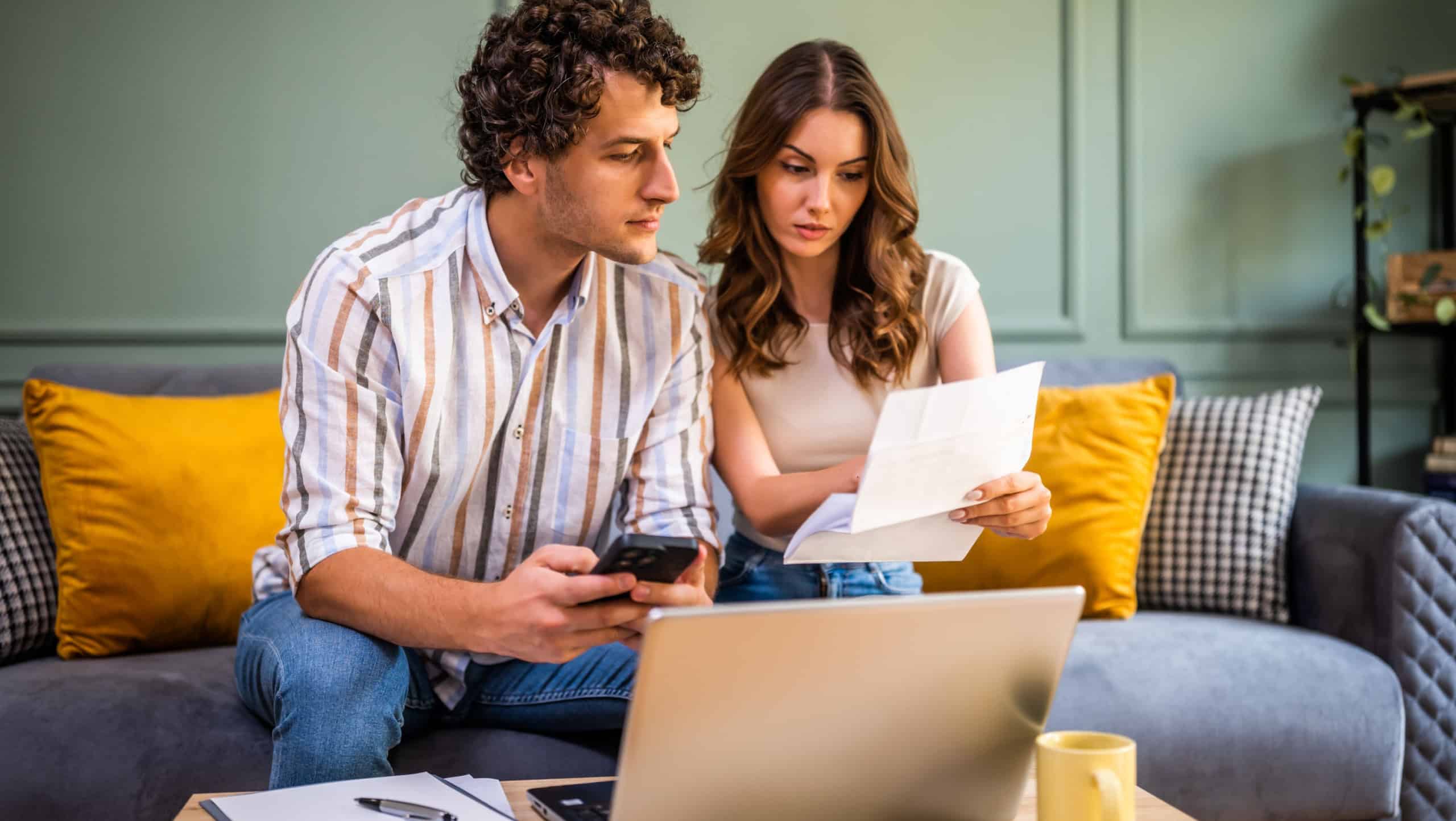 Couple discussing home finance while checking bills. They are checking financial documents and calculating family budget in living room.