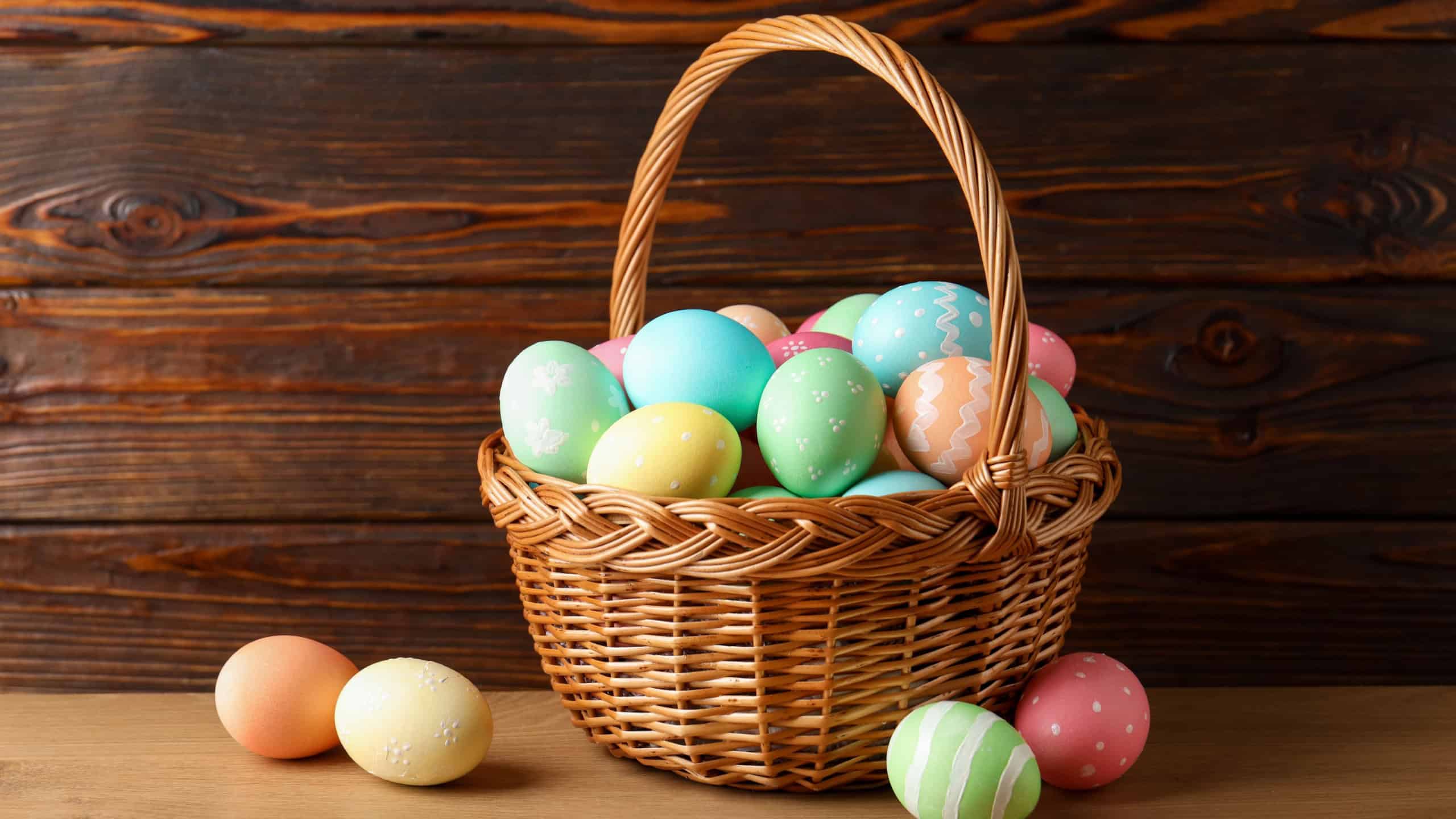 Beautiful Easter eggs in basket on wooden table
