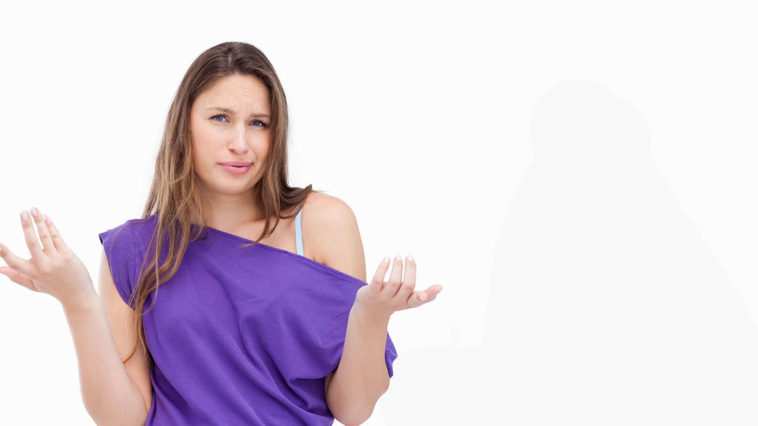 Female standing and shrugging puzzled in studio wearing purple off-shoulder top, visible bra strap.
