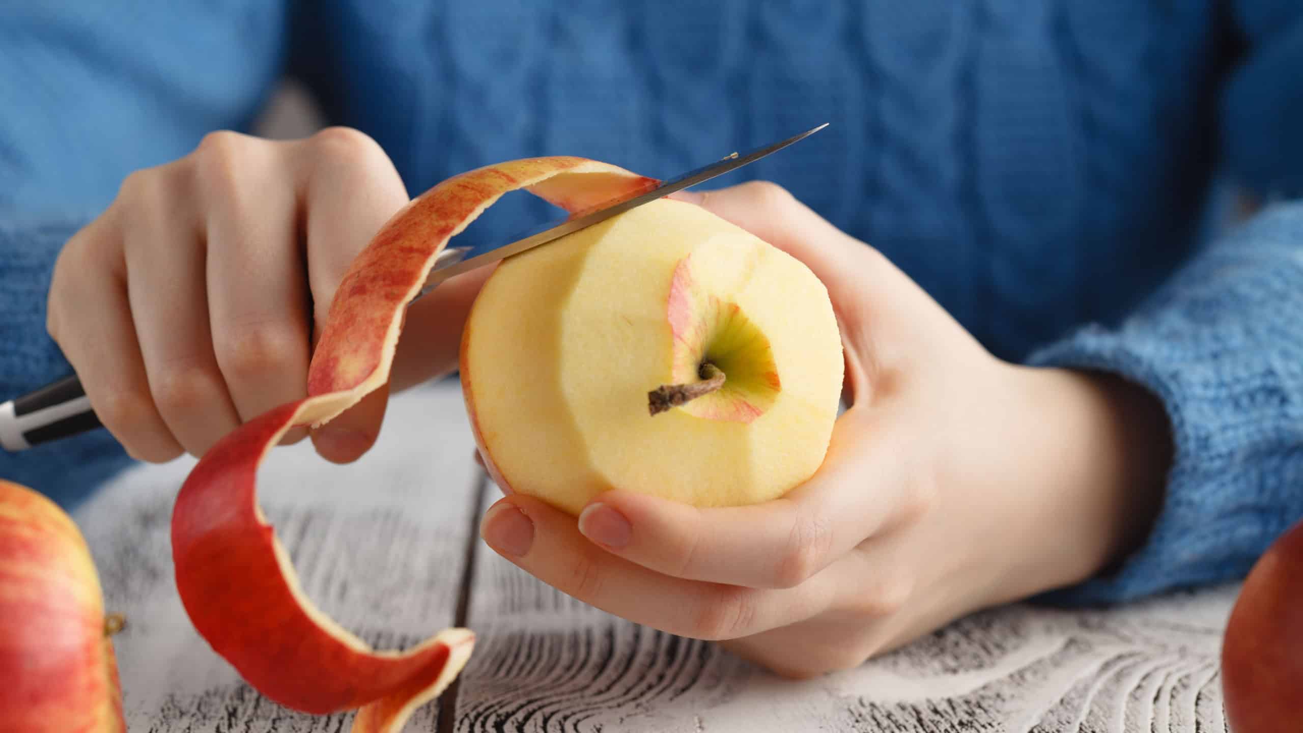 Girl peeling an apple on table