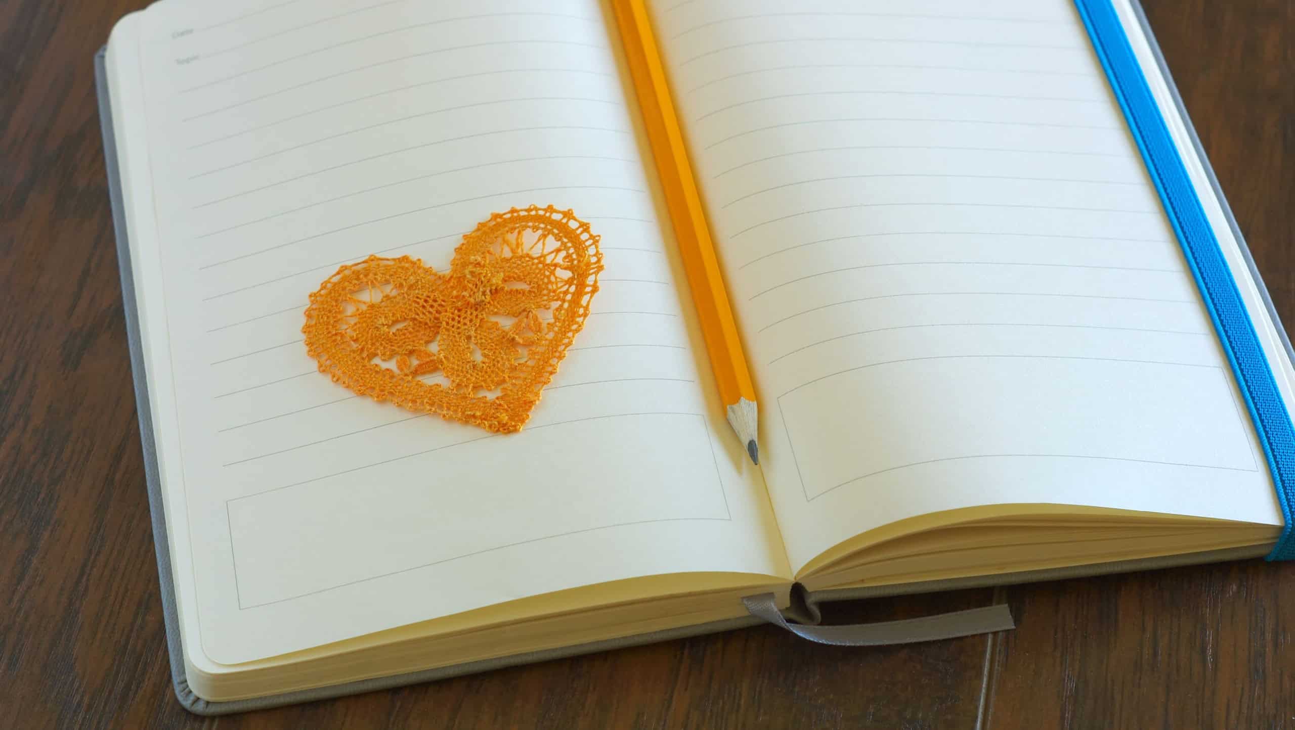 Heart symbol with pencil on open blank notebook page. Love message romance concept. Lyrics loveletter book.