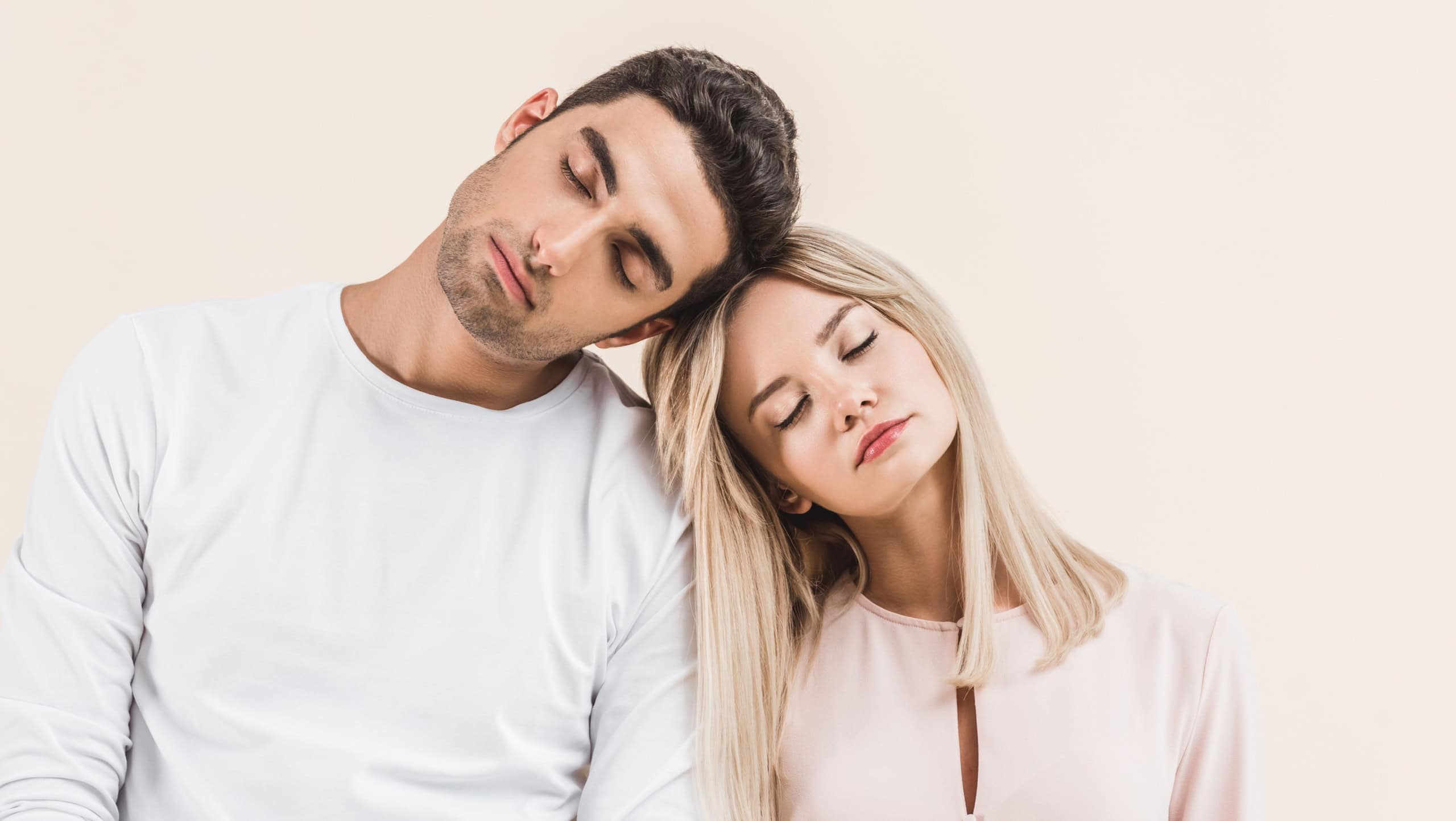 young couple sitting and sleeping isolated on beige