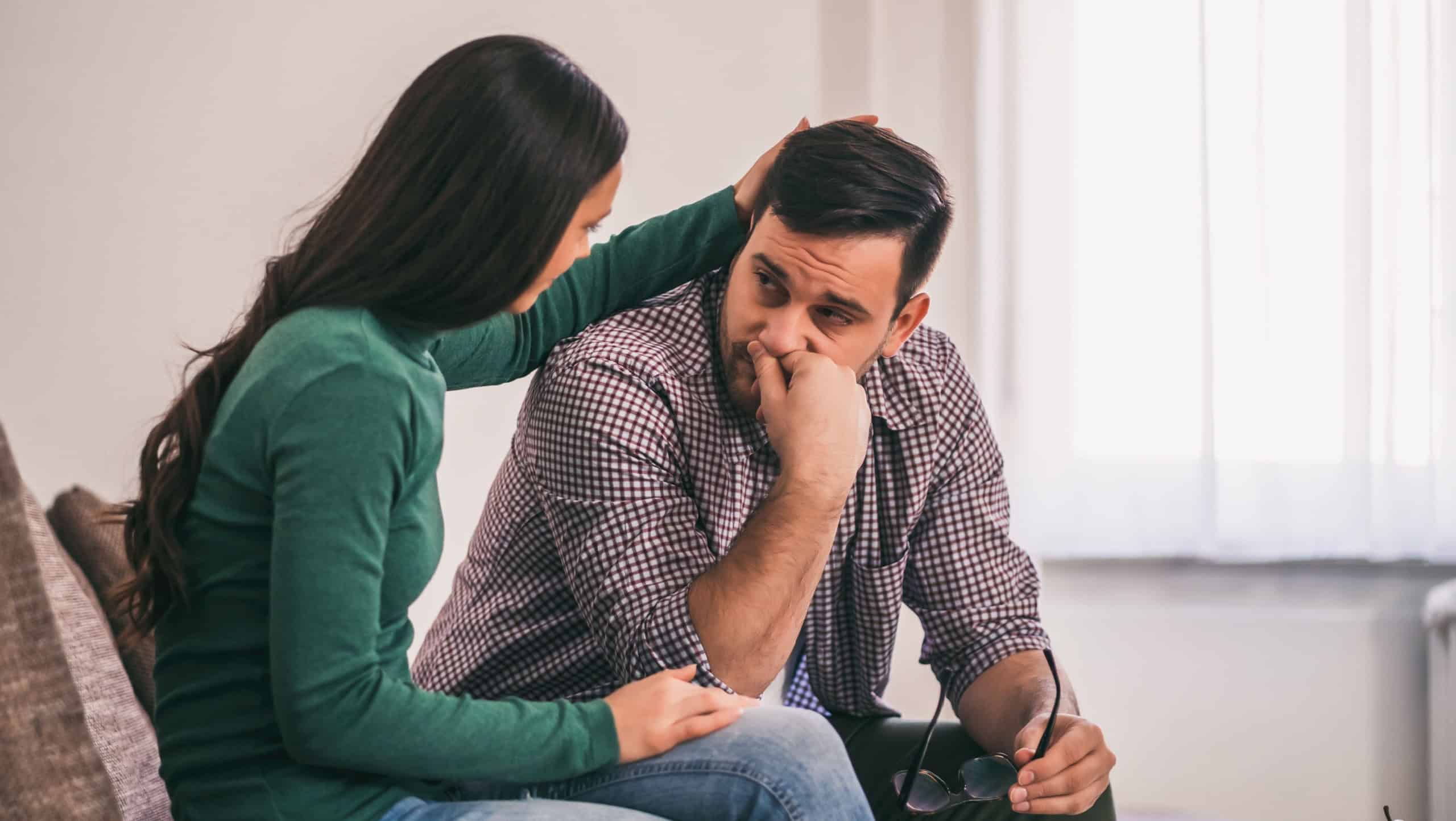 Man is sad and depressed, his wife is consoling him.