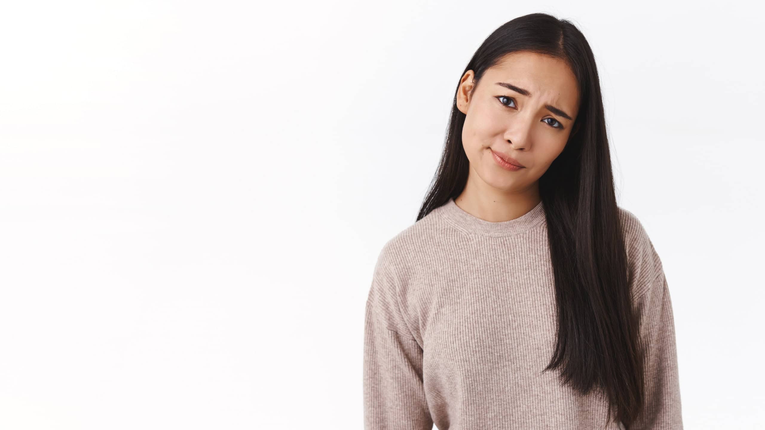 Skeptical, doubtful and displeased young east-asian girl smirk and tilt head, frowning look pity and upset, dont like results, feeling disappointed and bothered, standing indecisive white background