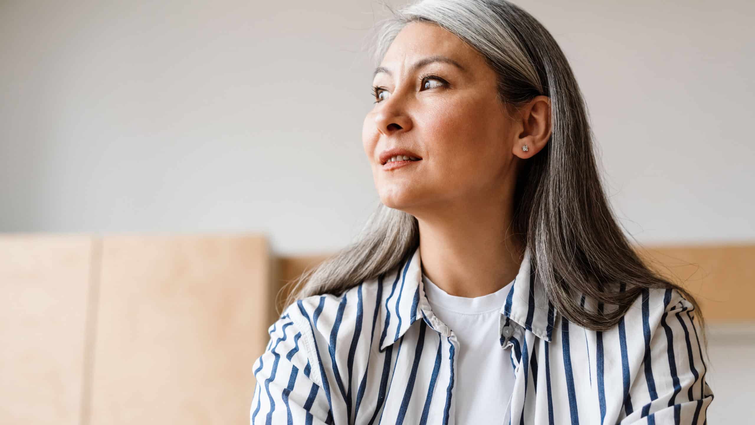 Focused white-haired mature woman working with laptop while sitting indoors