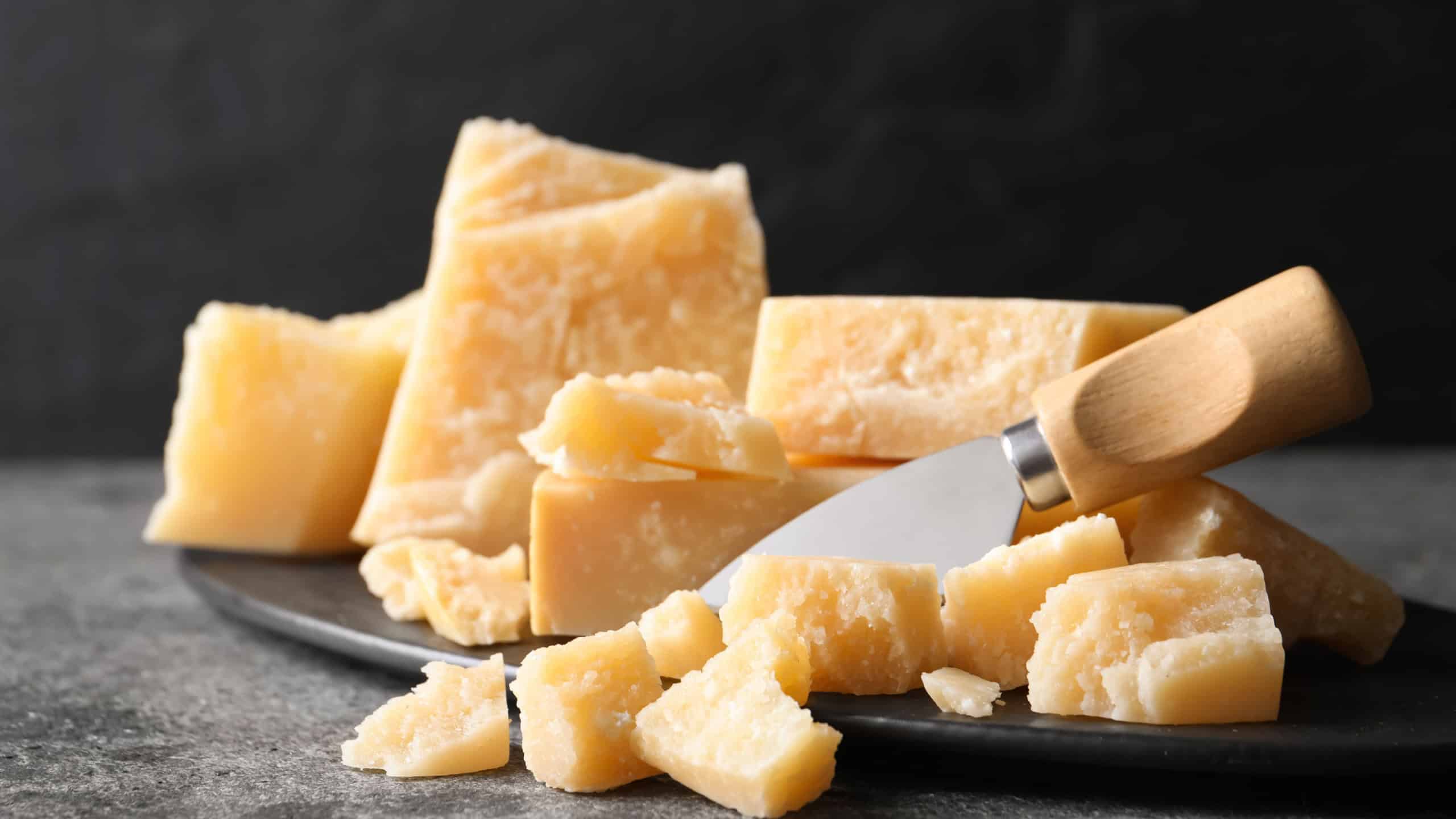 Parmesan cheese with board and knife on grey table