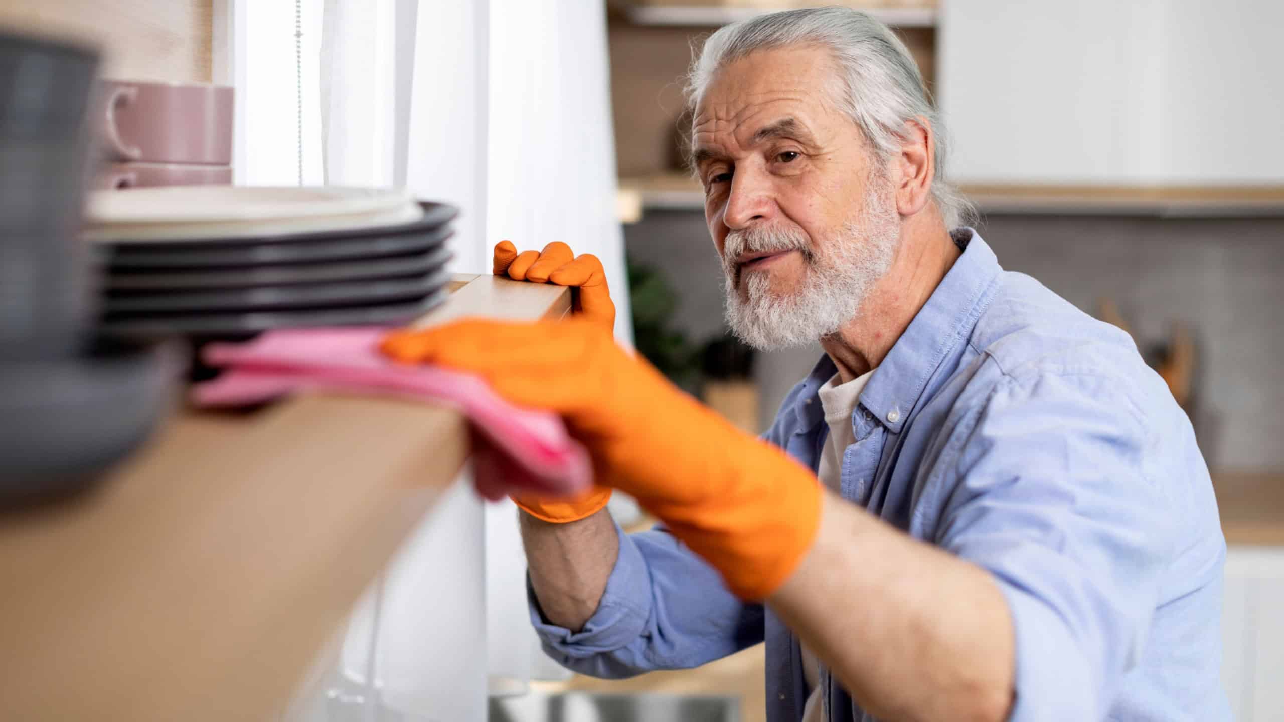 Man Cleaning Dust From Shelf In Kitchen, Tidy Elderly Gentleman Cleaning Home, Aged Male Suffering Obsessive-Compulsive Disorder While Doing Domestic Chores, Closeup
