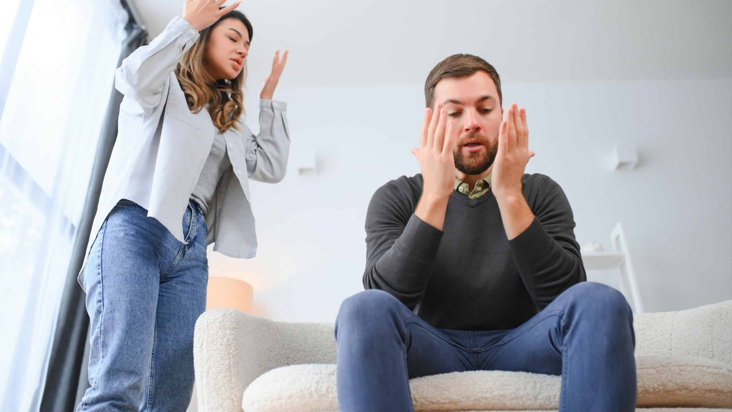 Family quarrel, man and woman sitting on sofa at home. angry woman yells at her husband.