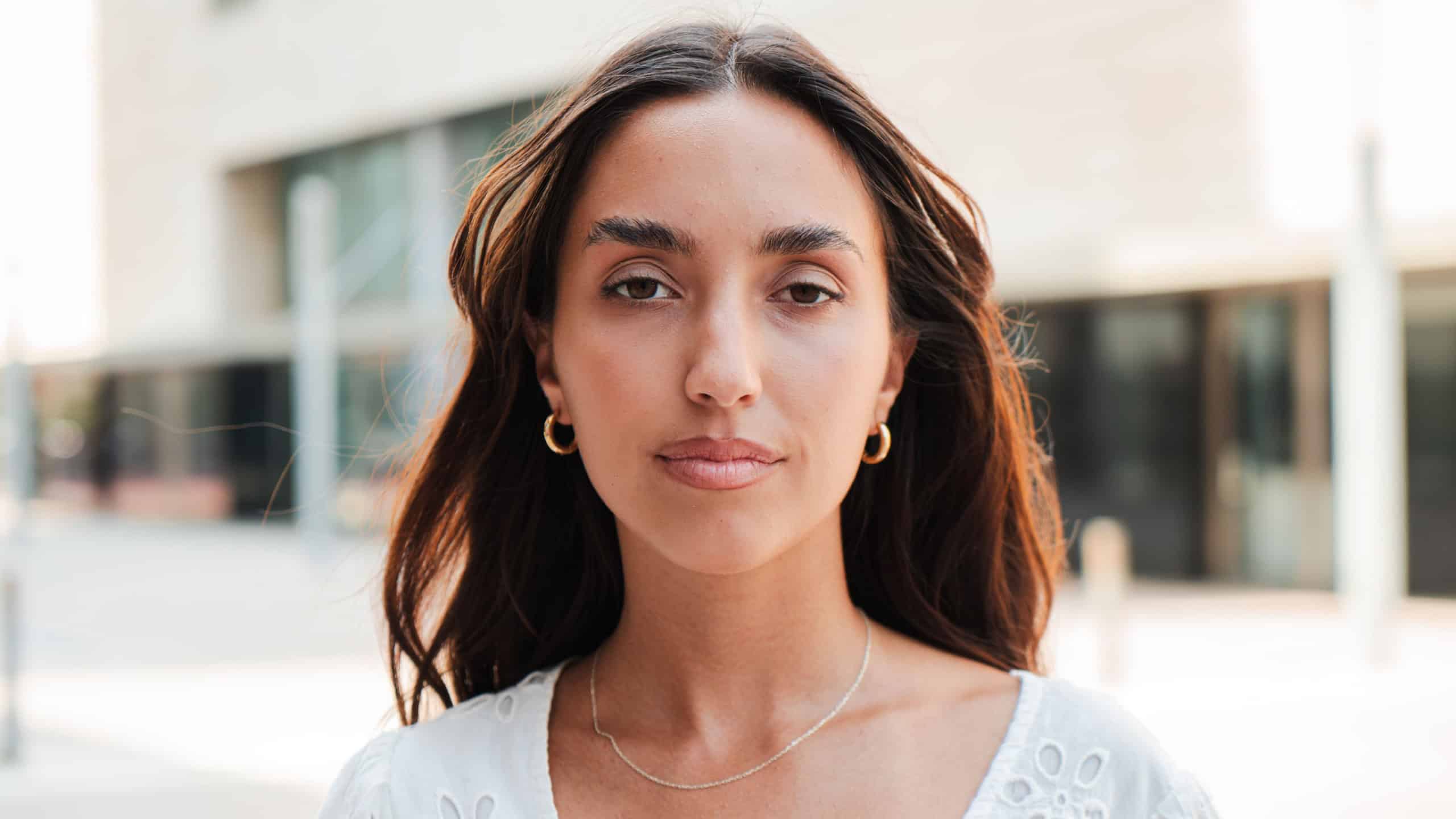Individual portrait of a Hispanic girl with a serious expression looking at camera. Young teenage woman staring front with a neutral demeanor. Only one Latin female gazing with a composed attitude