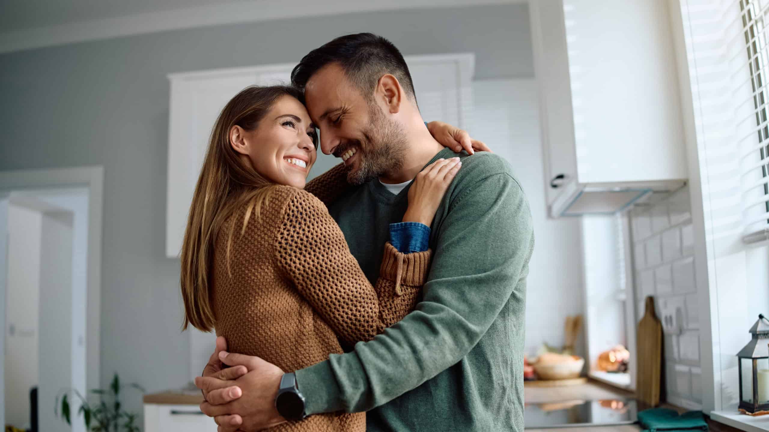 Affectionate couple embracing while enjoying in their new kitchen at home.