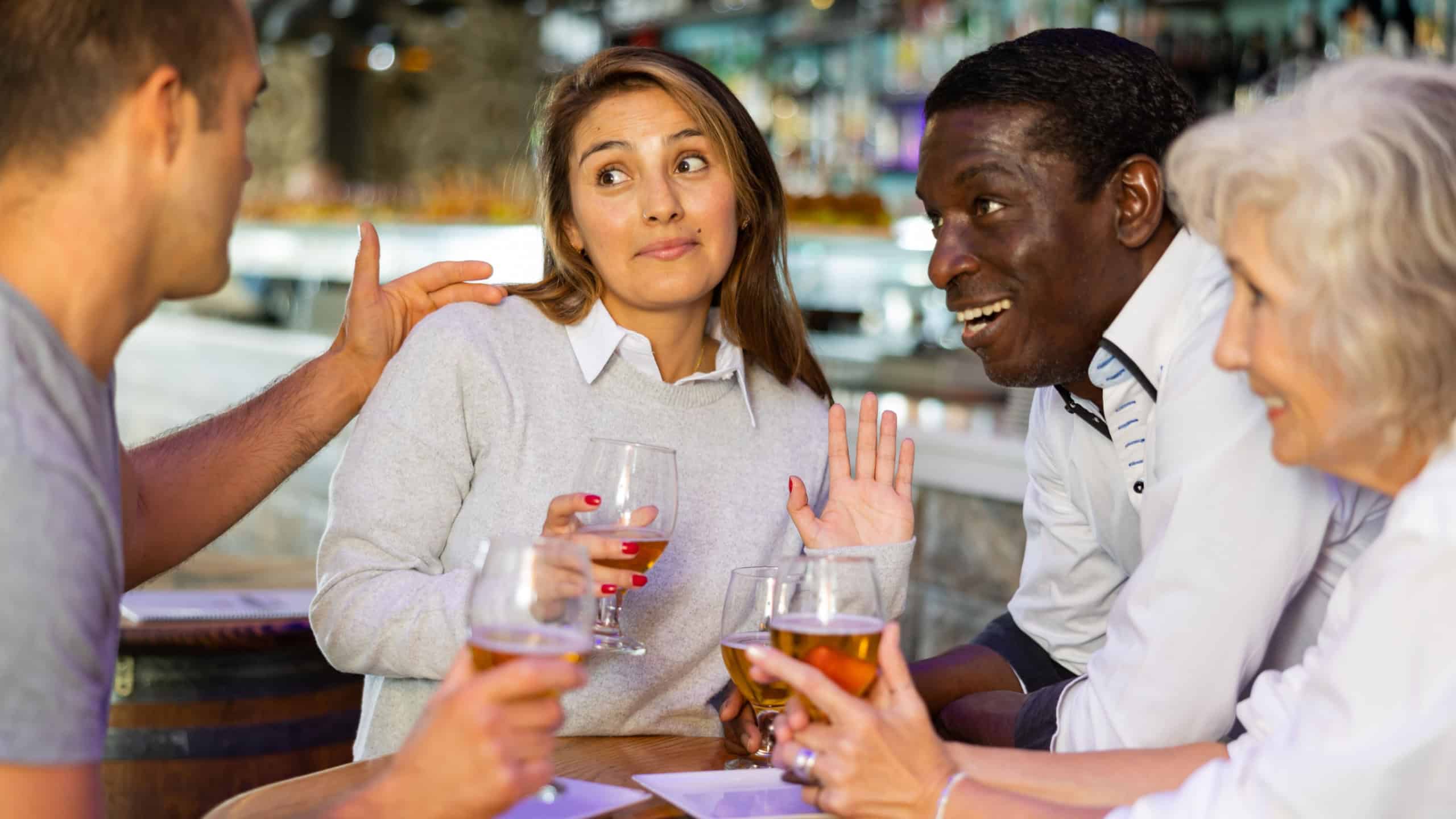 Diverse group having an awkward conversation at a bar with beer..