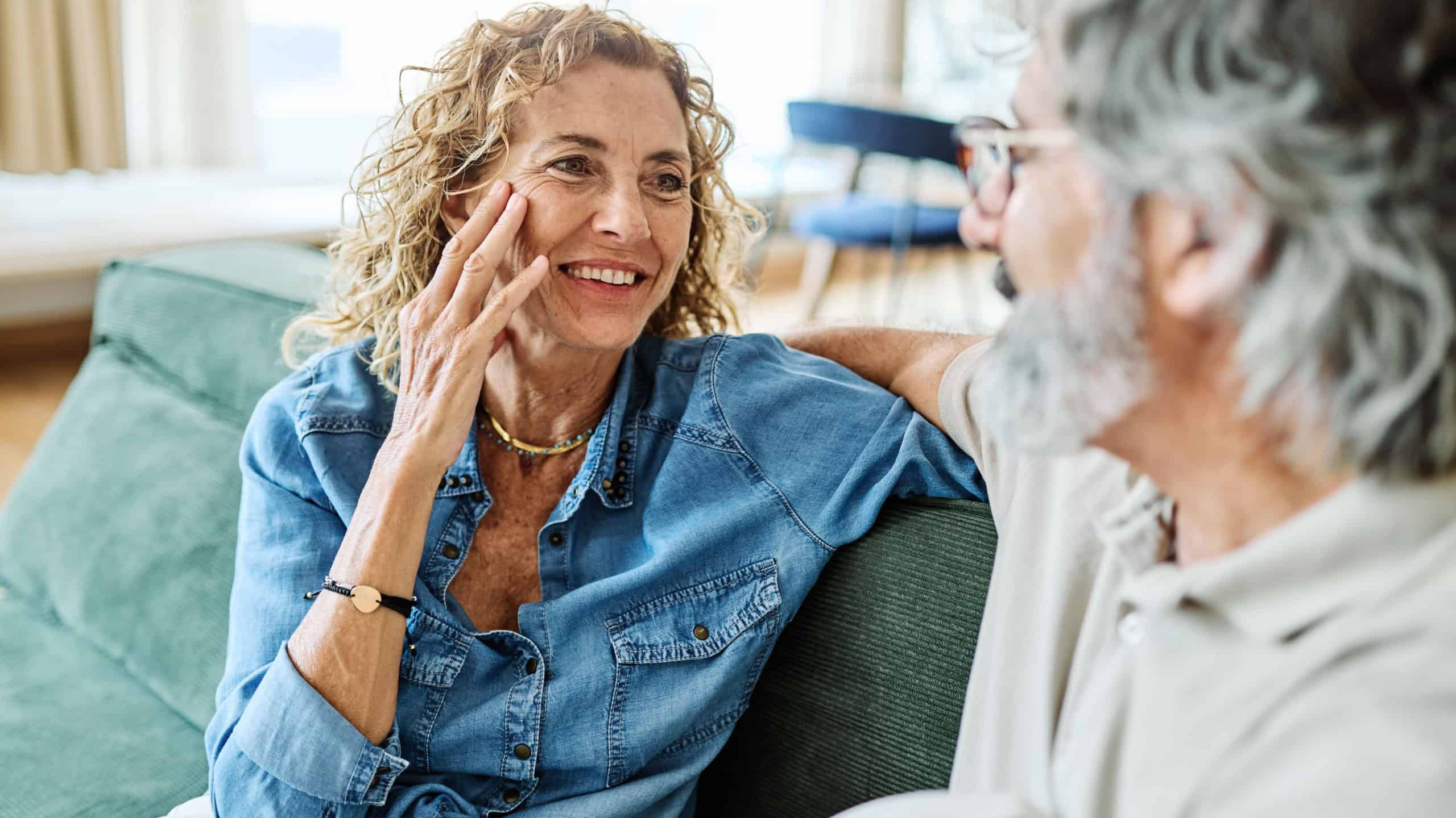 Portrait of a happy senior couple embracing talking at home