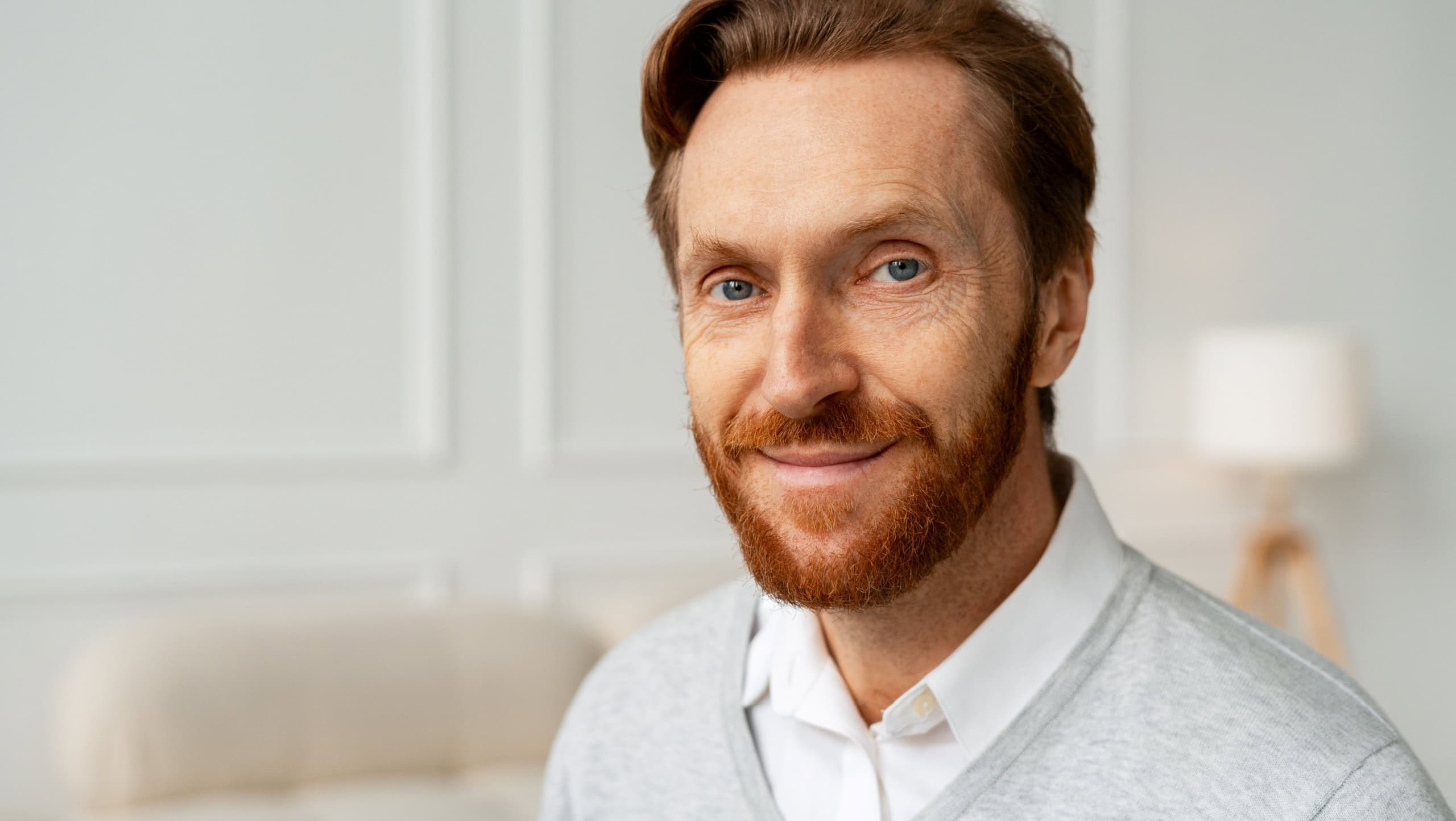 Confident ginger man with a red beard and blue eyes smiling warmly, expressing professionalism and approachability