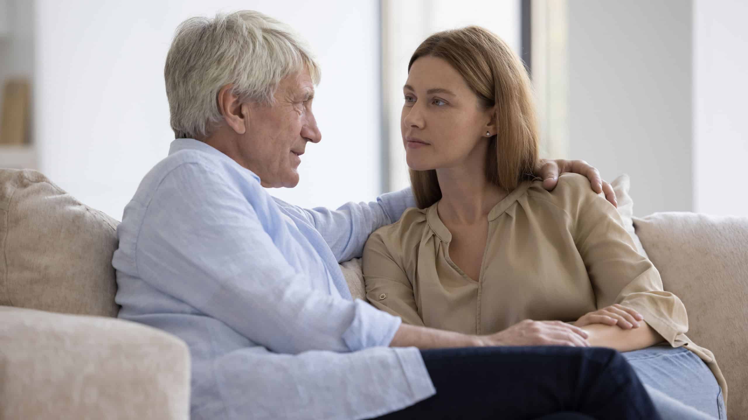 Conversation of older man and adult daughter. Serious attentive young woman sit on sofa and listen old dad talking about health problems, life concerns, share news feeling support form loving daughter