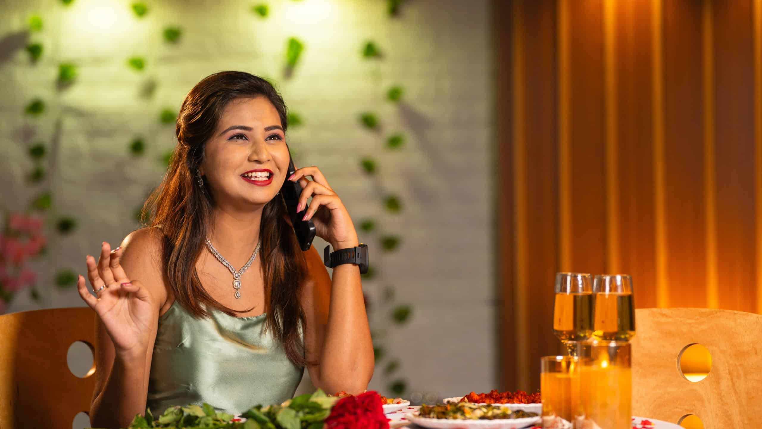 happy excited woman speaking on mobile phone call during candlelight dinner at restaurant while waiting - concept of valentines day, date night plan and glamours.