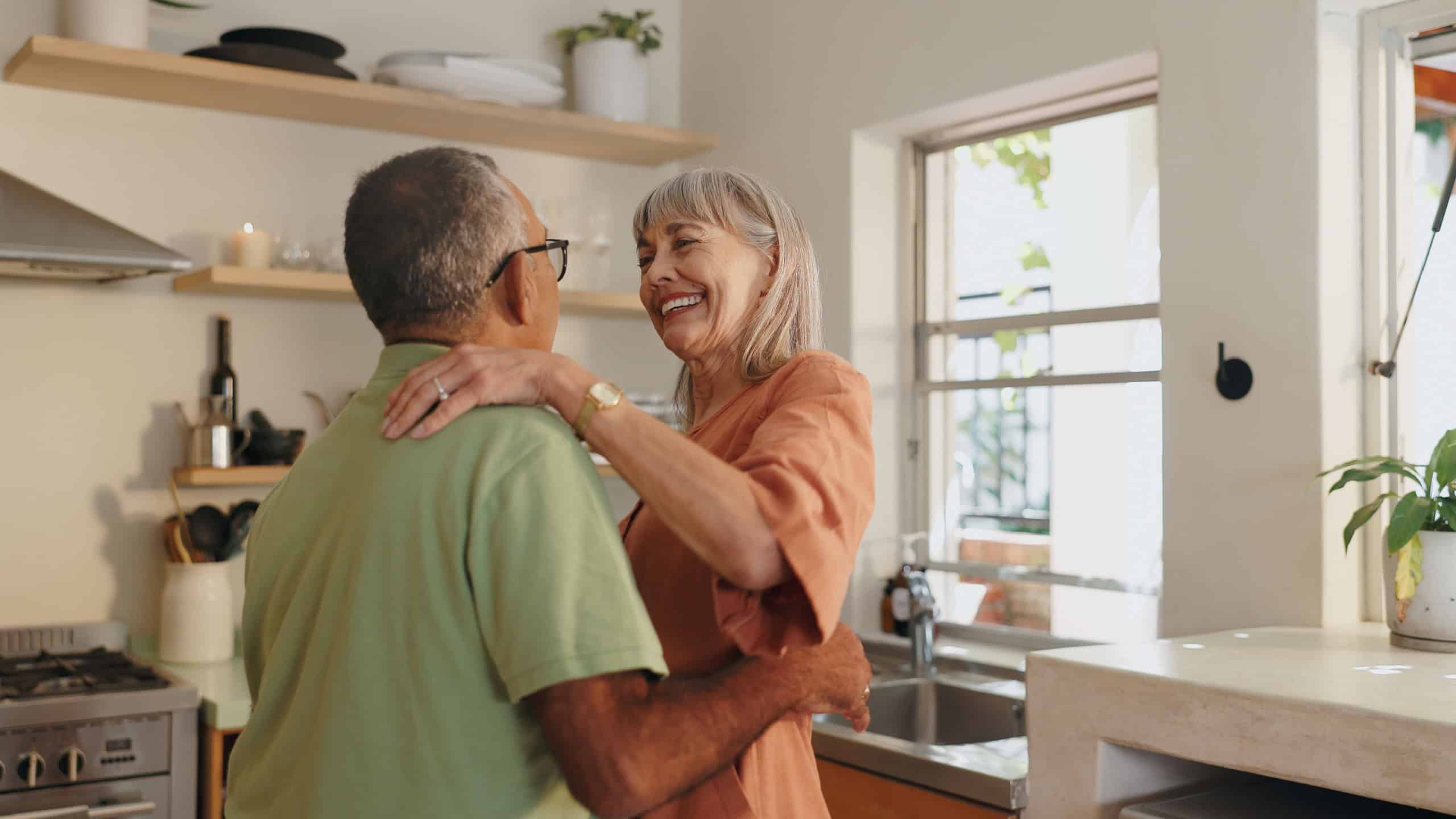 Senior couple, love and dancing in kitchen for retirement and healthy relationship with romance. Interracial marriage, old man and woman with dance steps in home for support and happiness together