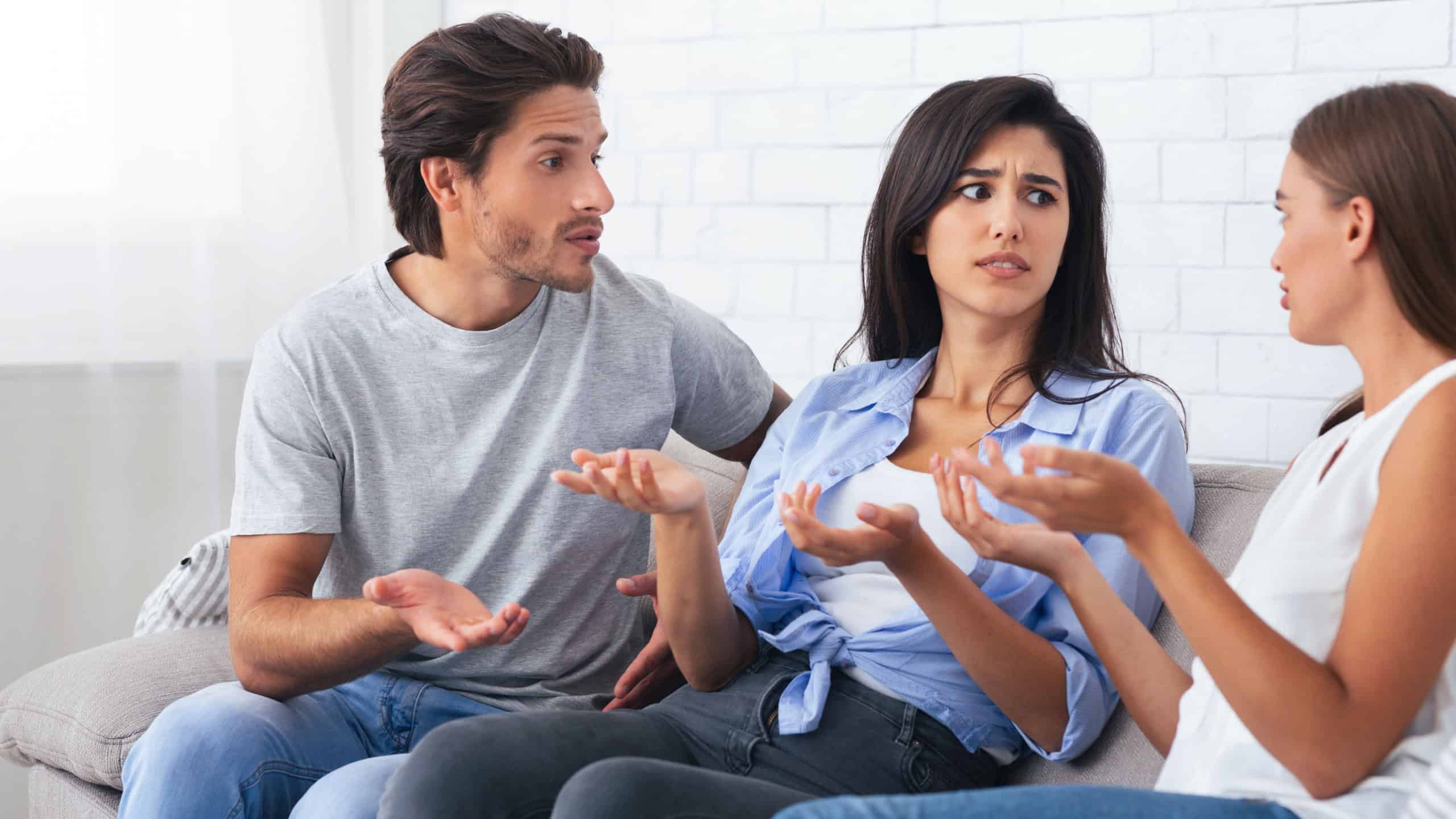Misunderstanding In Friendship. Three Angry Friends Having Quarrel Arguing Sitting On Sofa At Home. Selective Focus