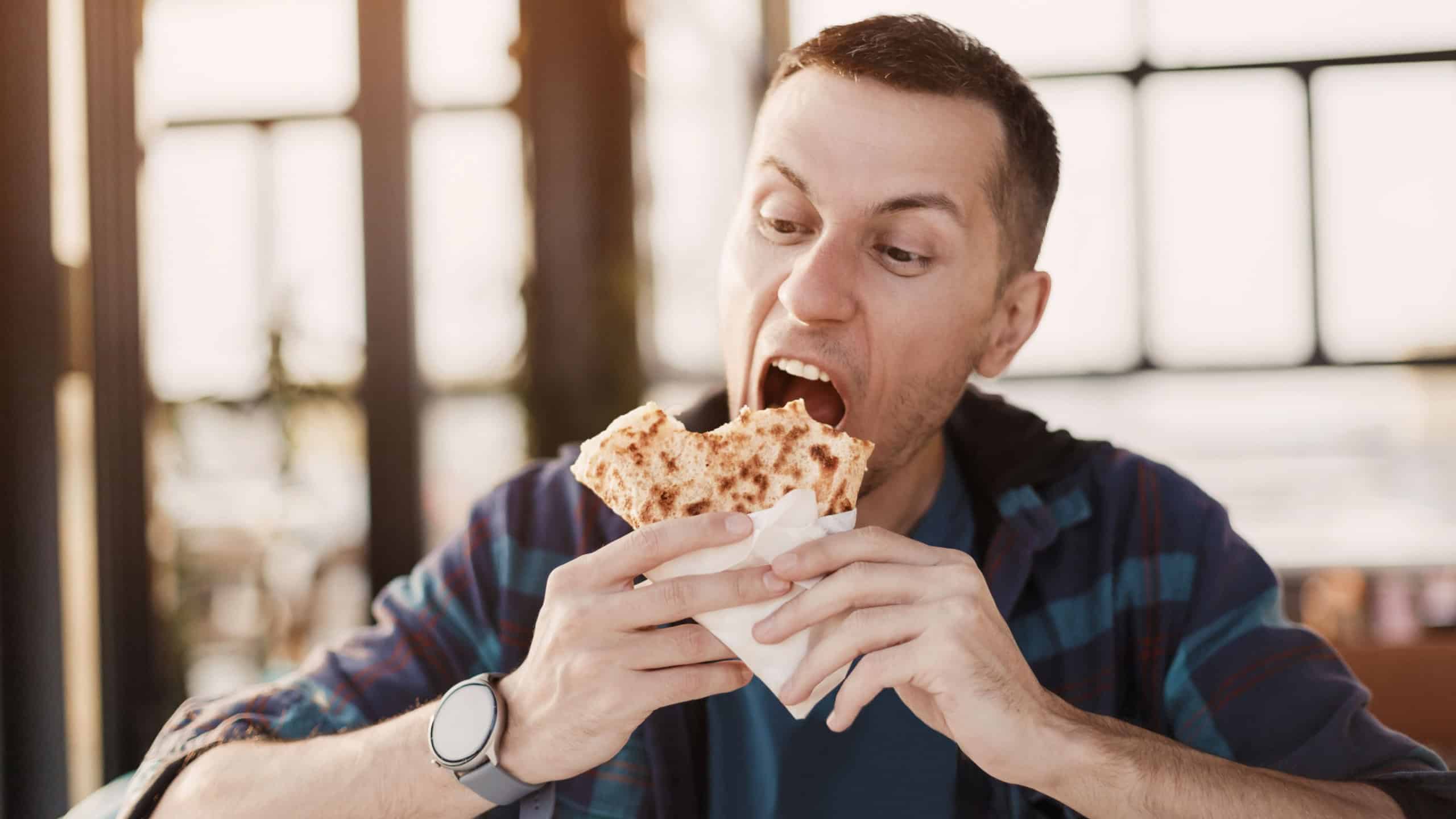 Young man savoring a delicious sweet crepe while seated at a restaurant table, enjoying the flavors of casual dining during lunchtime